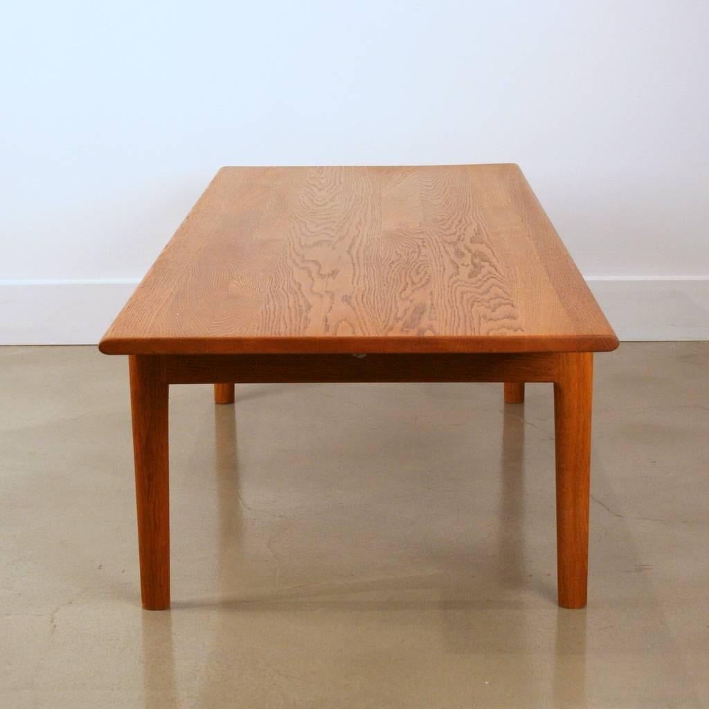 Beautiful solid oak coffee table features the wonderful design of Hans J. Wegner for Andreas Tuck. Complete with trademark signed, and makers stamp. Recently refinished top surface. Sleek, simple modern design is perfect for any space.