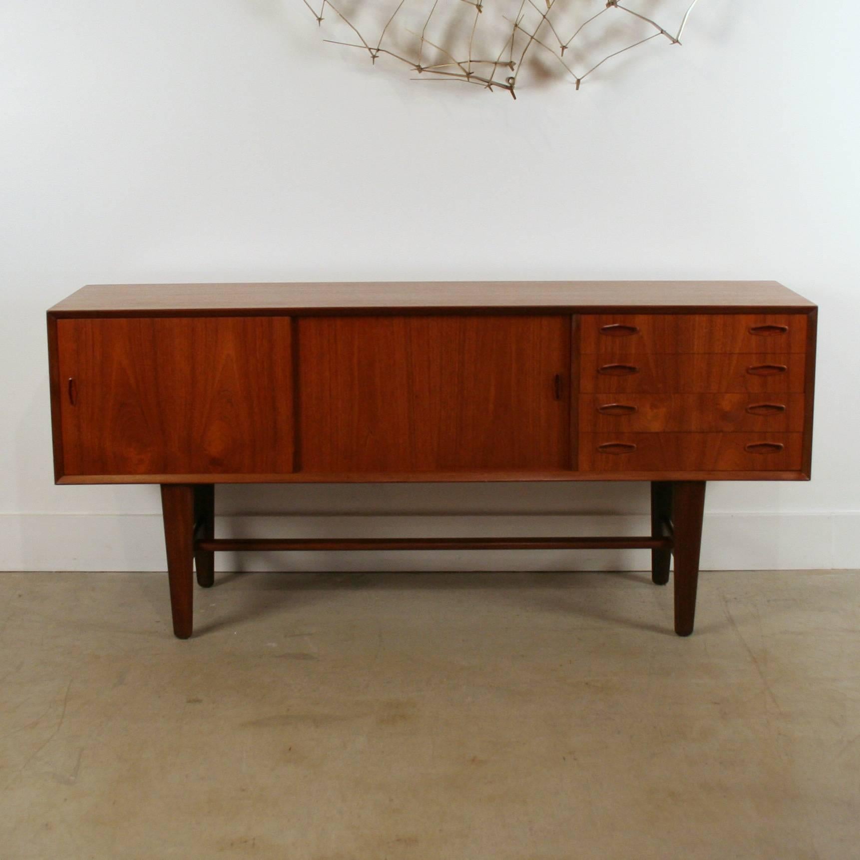 Wonderful vintage Danish teak sideboard. Two sliding doors open onto two storage spaces with a single shelf in each. This piece also features four drawers with dovetail joinery. Doors and drawers all feature delicate, inset framed finger pulls. Set