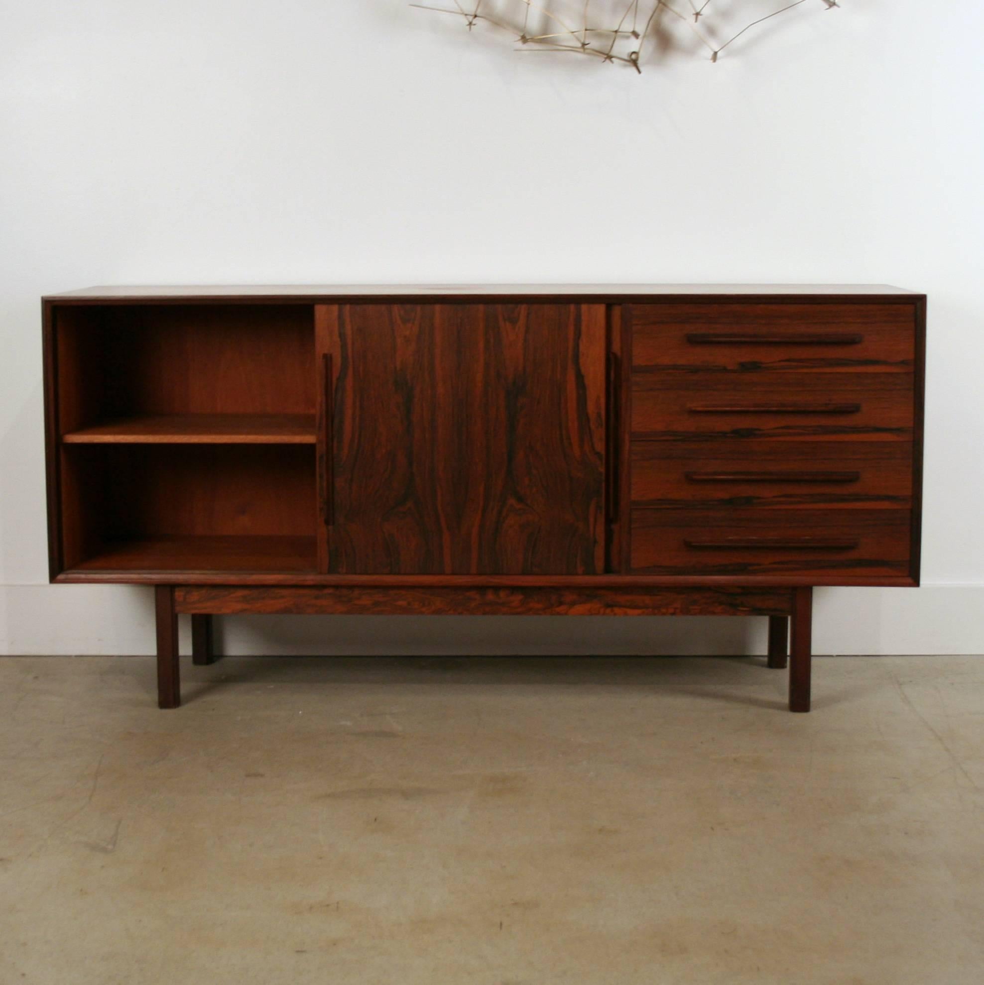 Exquisite vintage Danish sideboard crafted out of Brazilian rosewood. The patina is highlighted on the two sliding doors. Bank of four drawers along the right facing side. Solid rosewood edging, pulls and legs give this piece extra elegances. Made