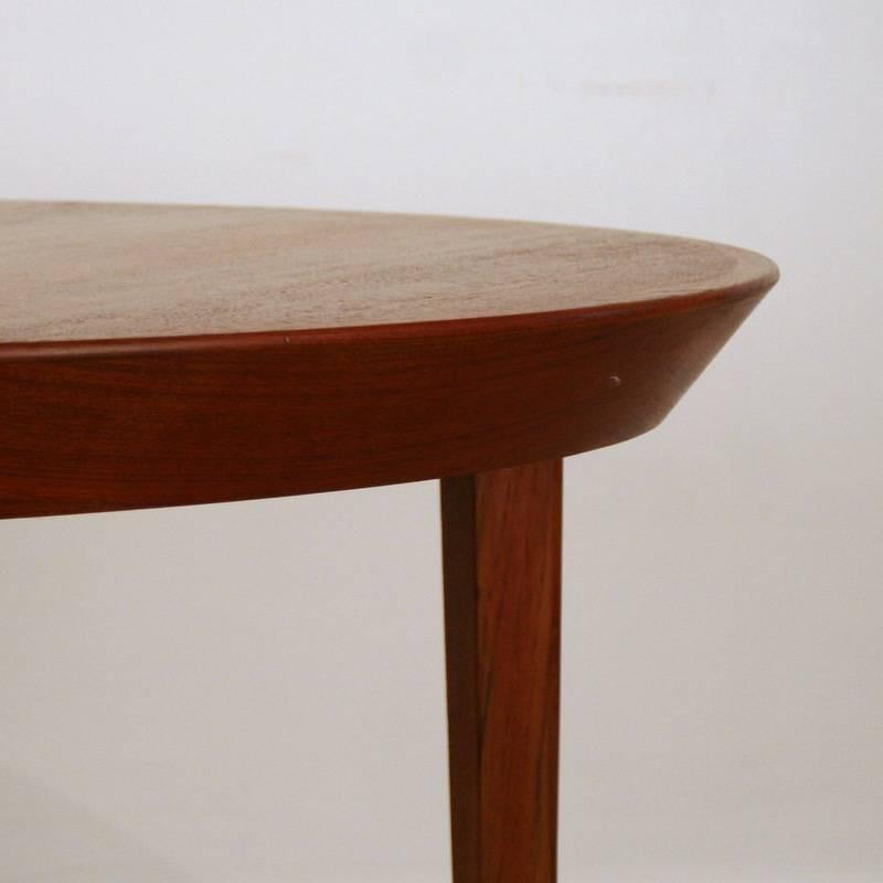 Stunning round teak dining table by Kai Kristiansen. Sleek angled apron. Expandable with two independent leaves. Resting on solid teak legs. Two leaves at 20" each. Made in Denmark.