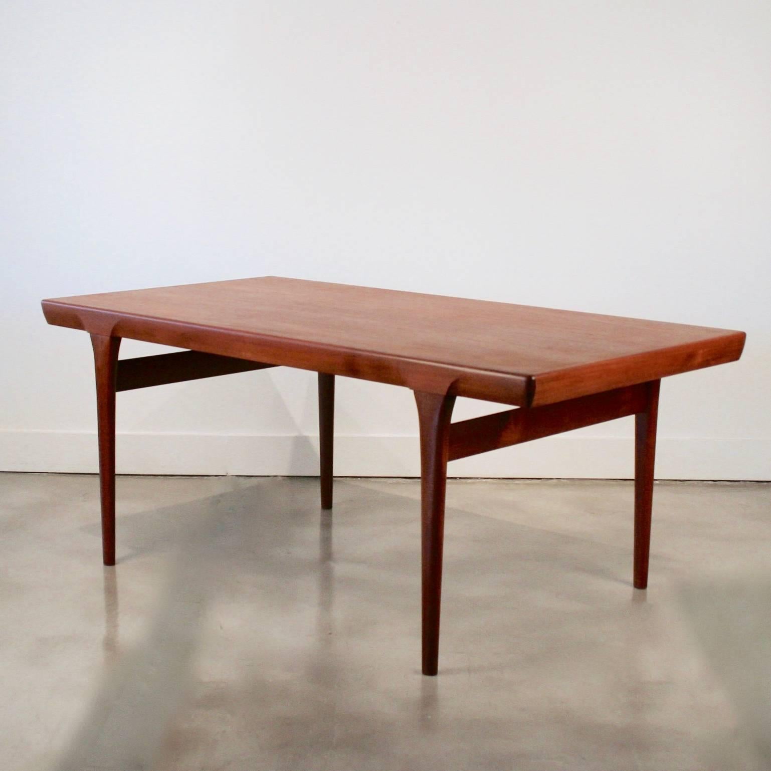 Stunning vintage Danish teak table designed by Kofoed Larson featuring wonderfully crafted leg detail and two leaved stored underneath the table at 14 inches each. Made in Denmark.
     