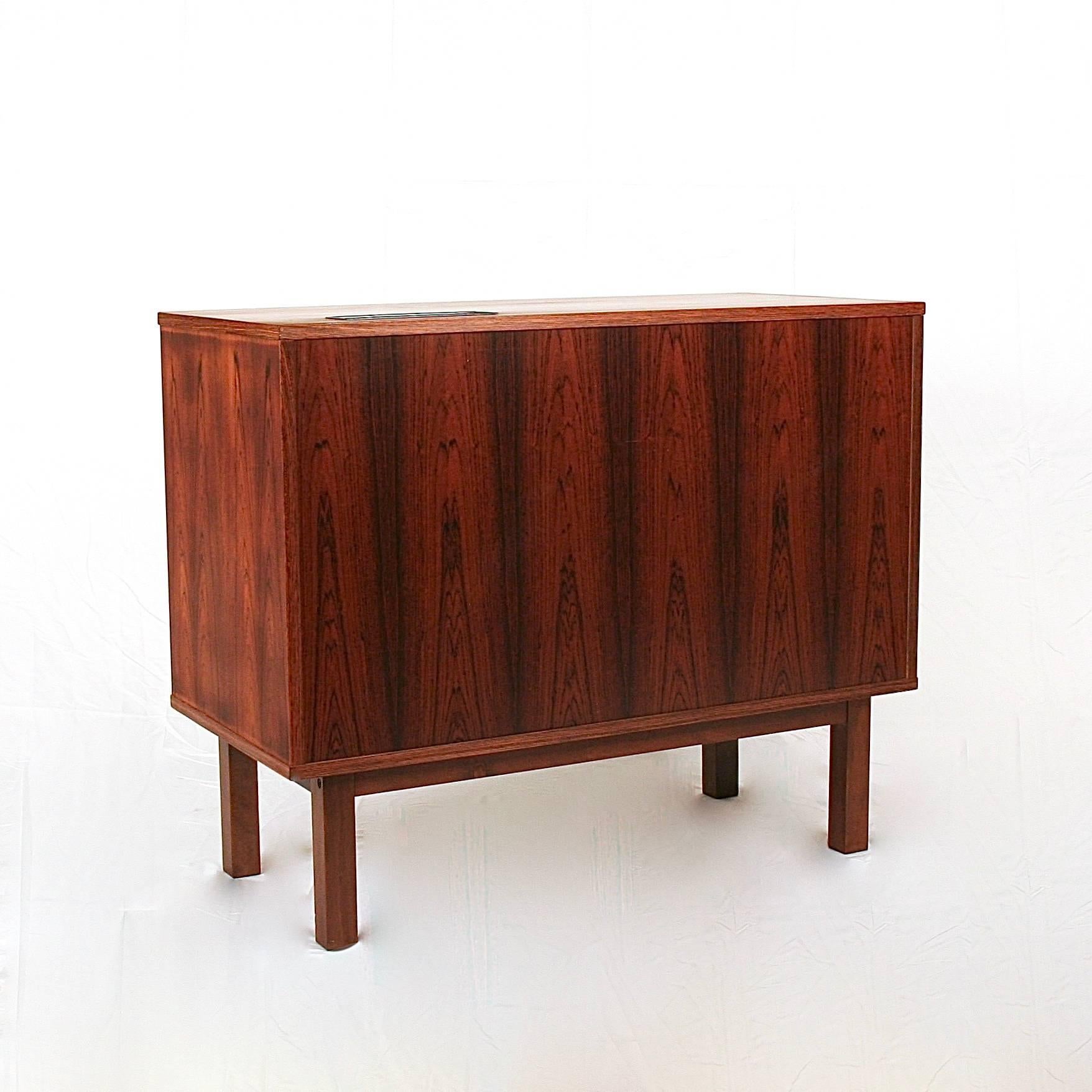 Vintage Danish rosewood cabinet with single tambour door. The door opens onto a split storage space, ideal for a mini bar or record player. A vent has been installed into the top of this piece which suggests it was used to house a mini fridge at