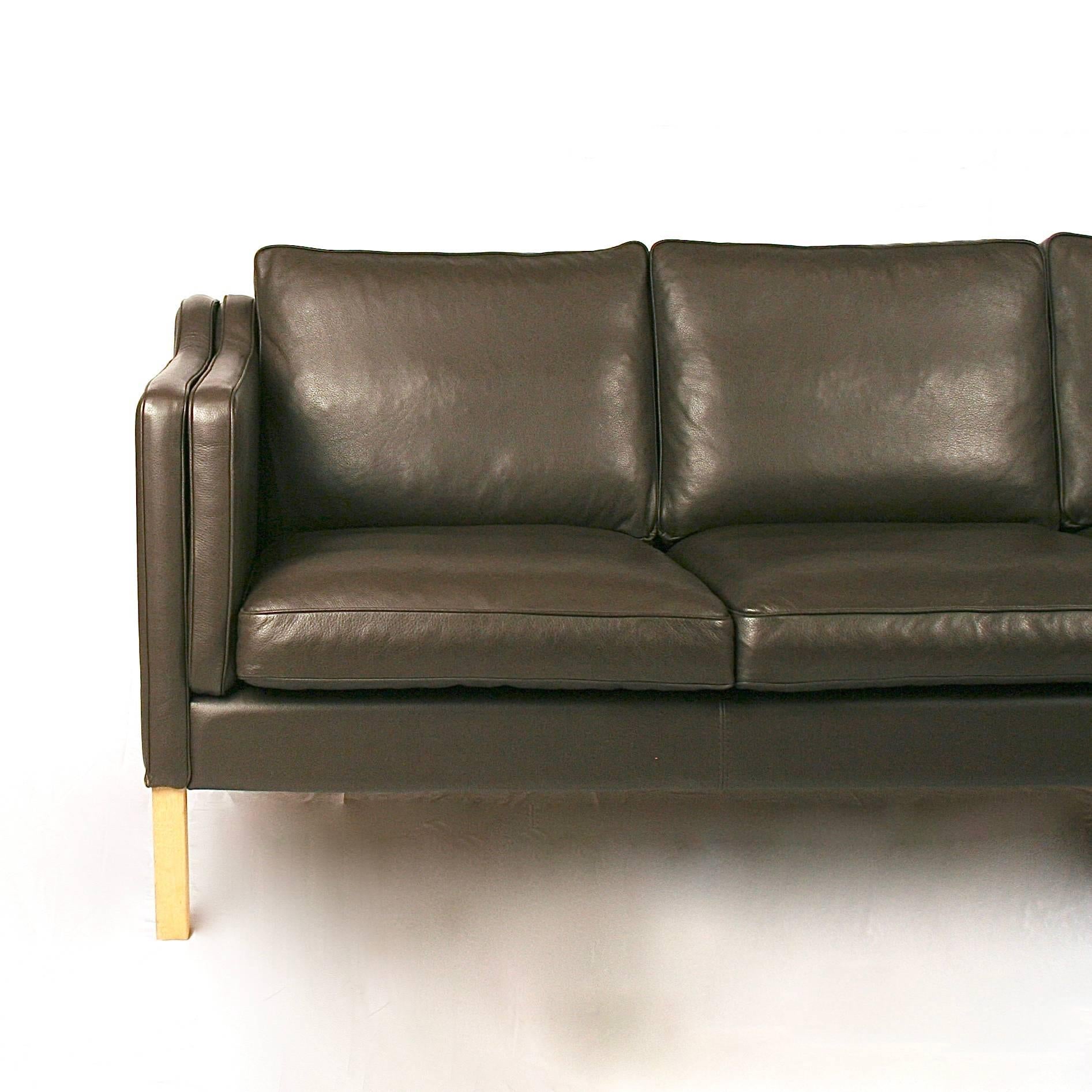 Vintage Danish chocolate brown leather sofa. This piece features light oak legs, piping detail on arms and cushions and three over three loose seat and back cushions. Classic Mid-Century Danish design. Made in Denmark.