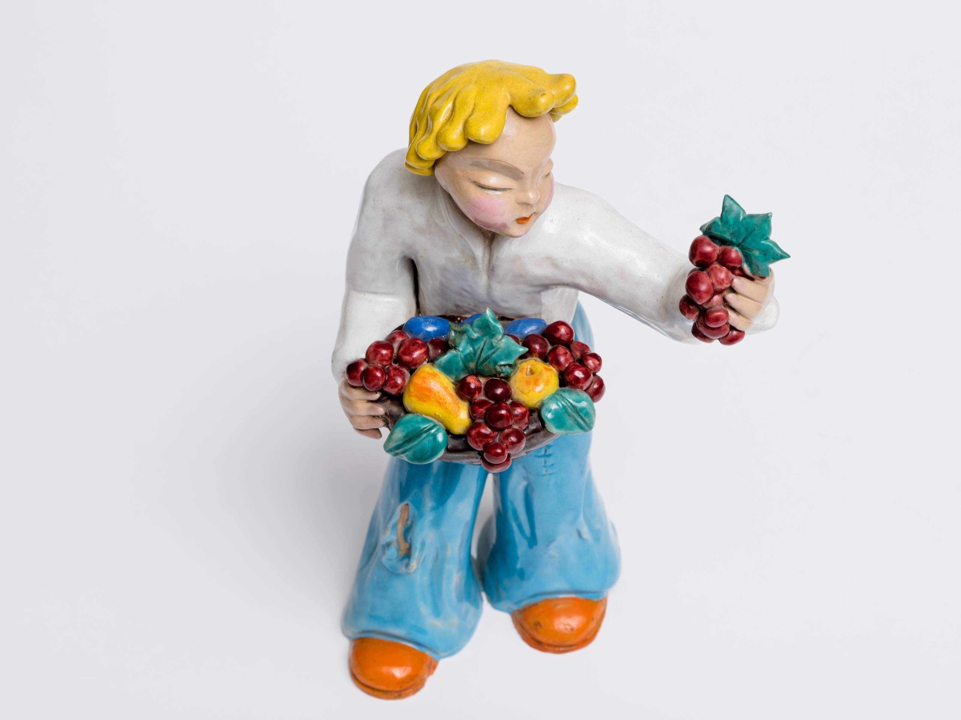 Fabuleuse et grande sculpture figurative de Maria H. Rahmer (1911-1998) représentant un garçon tenant des fruits, datant des années 1930 et provenant de Hongrie. Excellent état de la céramique avec la signature H. Rahmer sur le côté de la jambe. 