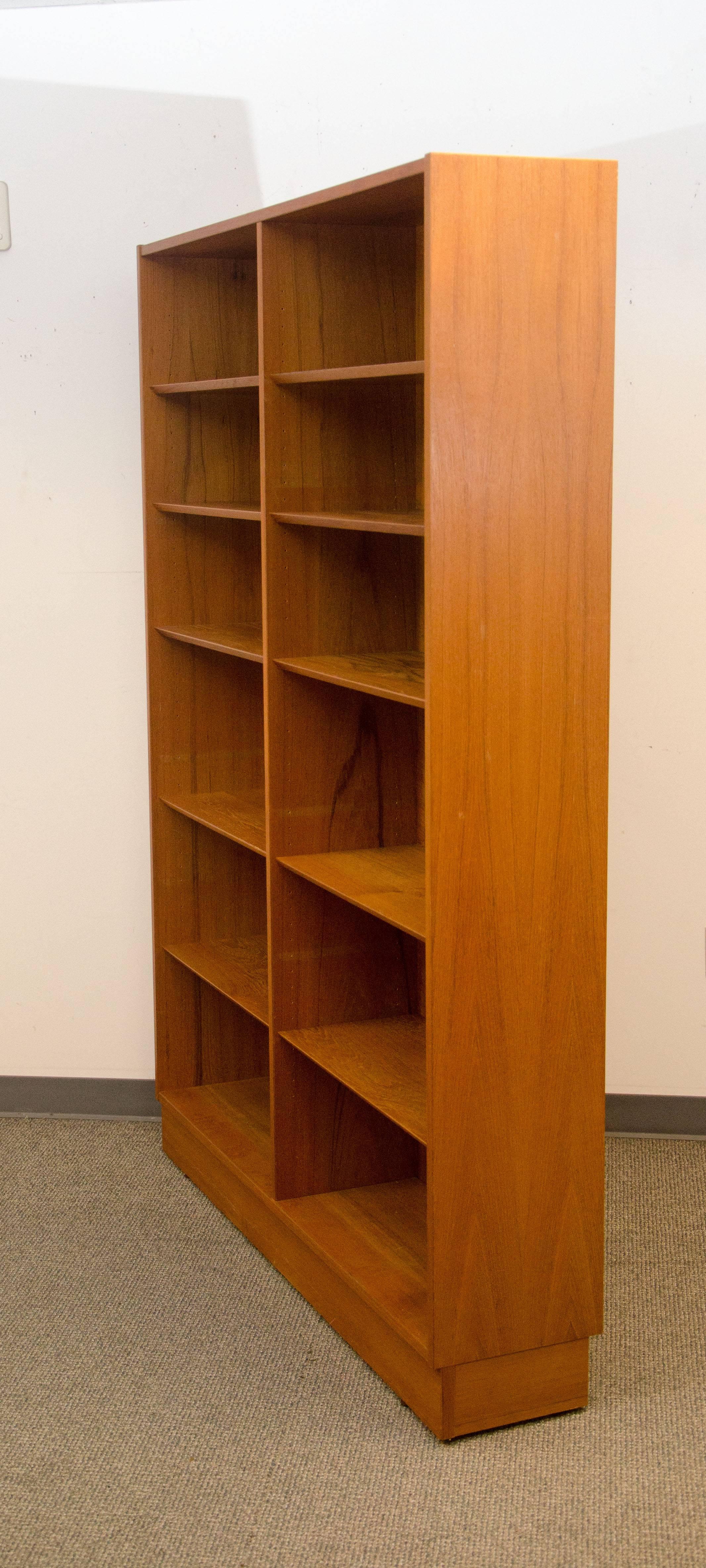 Spacious Danish teak bookcase with ten shelves, two shelves are stationary and eight are adjustable. The shelves have a decorative bevel on the front edge. The shelves are mounted on an adjustable wire system that is not visible when shelves are