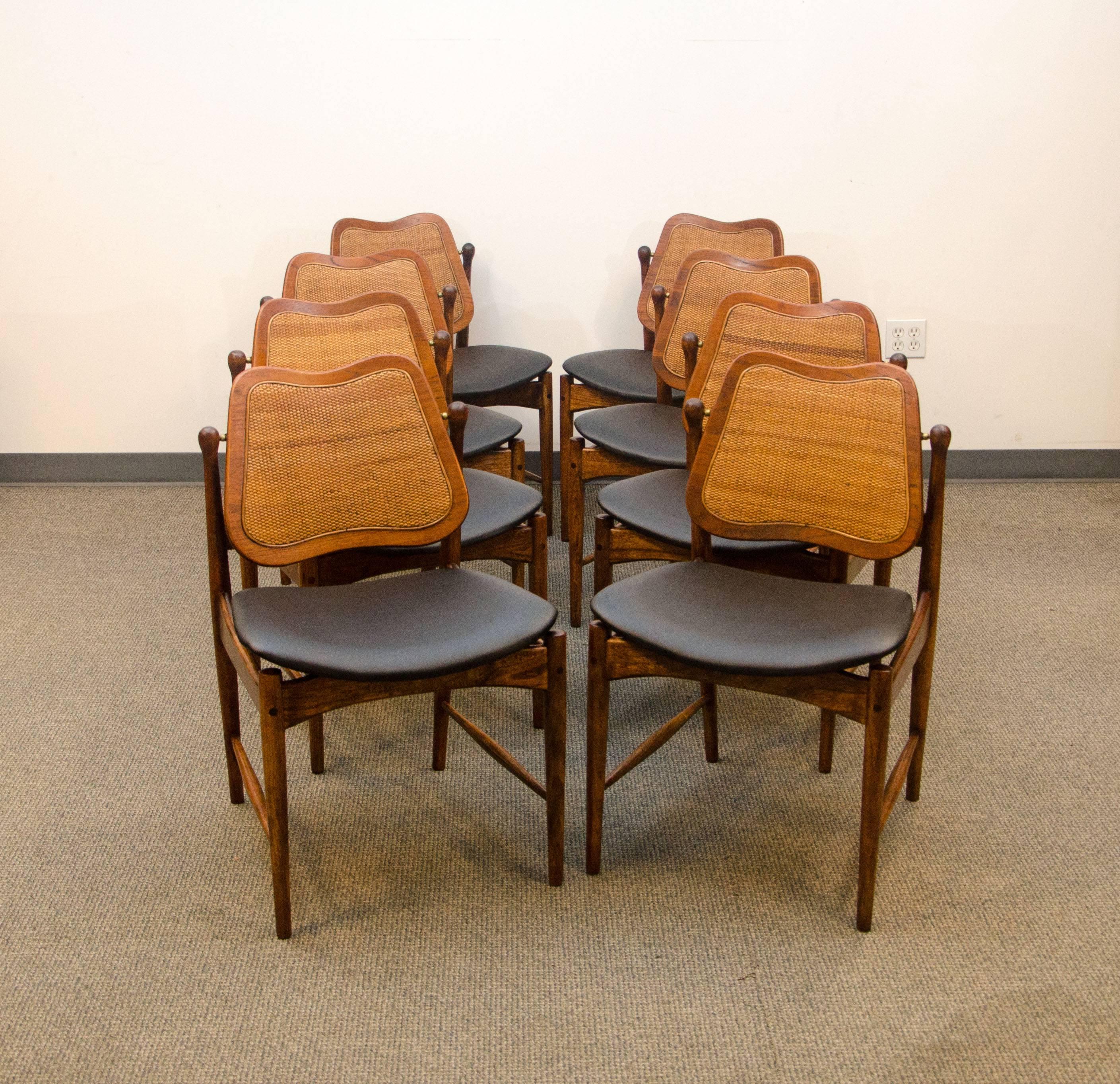 Rare set of eight Danish dining chairs. The teak backs swivel and have their original caned inserts. The seats have a floating design in the way they attach to the frame. The swivel backs have a wood crossbar behind them to keep them in place. There