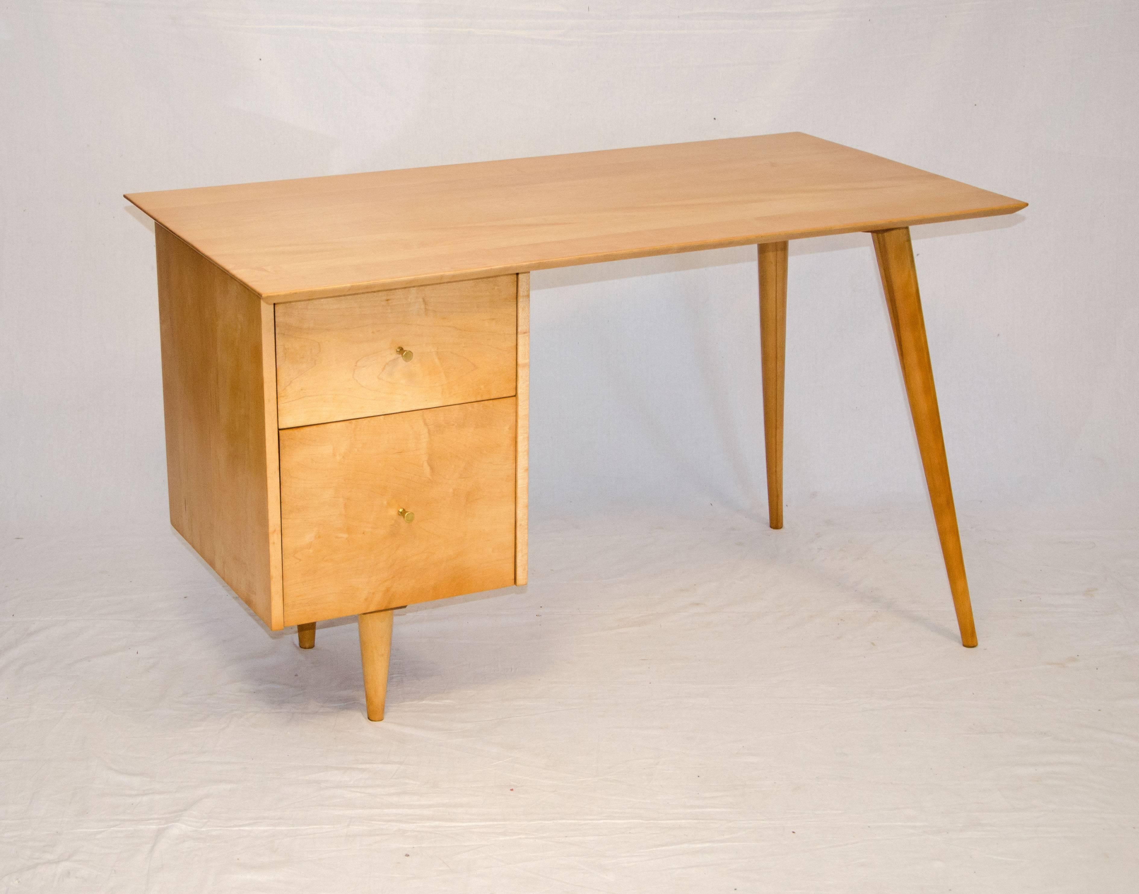 Solid maple medium size desk supported by drawers on one side and the signature angular tapered legs on the other. There is ample knee space without a center drawer. The top drawer retains most of the Planner Group label, bottom drawer is for