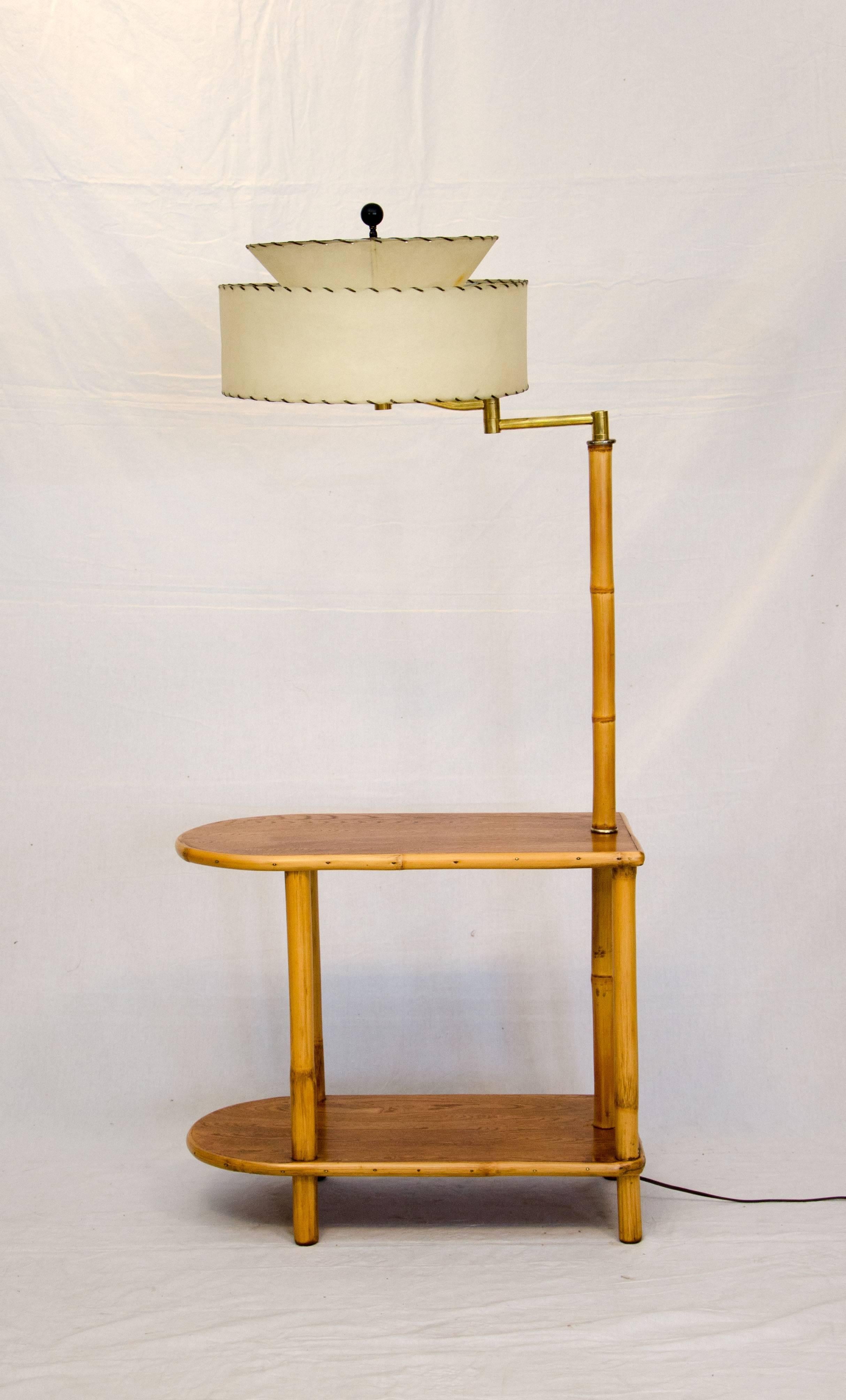 Rattan two-tiered end table with attached lamp and vintage shade. The lamp can be adjusted from side to side if used for reading. Lower tier would store books or magazines.