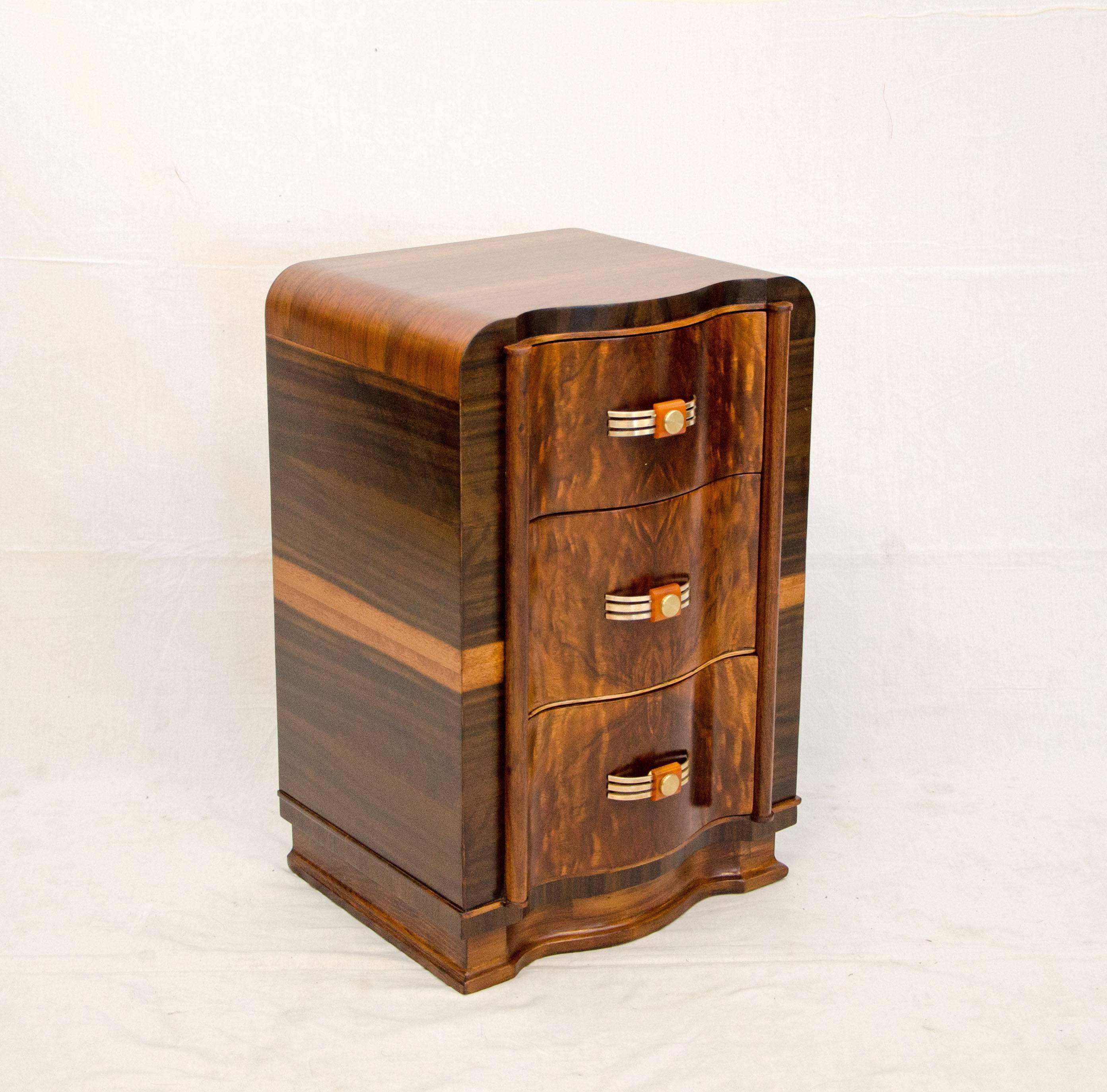 Curvaceous walnut Art Deco nightstand with serpentine drawer fronts and book-matched burl walnut grain patterns, also displays matched grain on the sides. Original brass and Bakelite pulls on all three drawers.

Matching dresser and vanity in