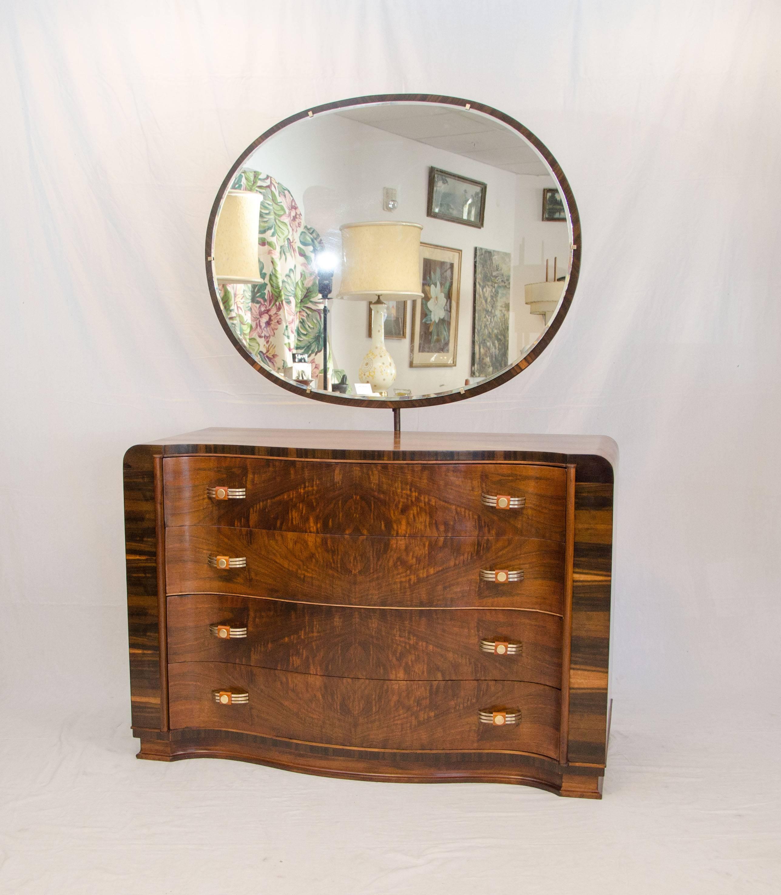 Curvaceous walnut Art Deco dresser with mirror, the drawer are serpentine and book-matched burl walnut grain patterns. The dresser sides also display beautiful grain patterns. The original drawer pulls are brass with Bakelite accents. The mirror is