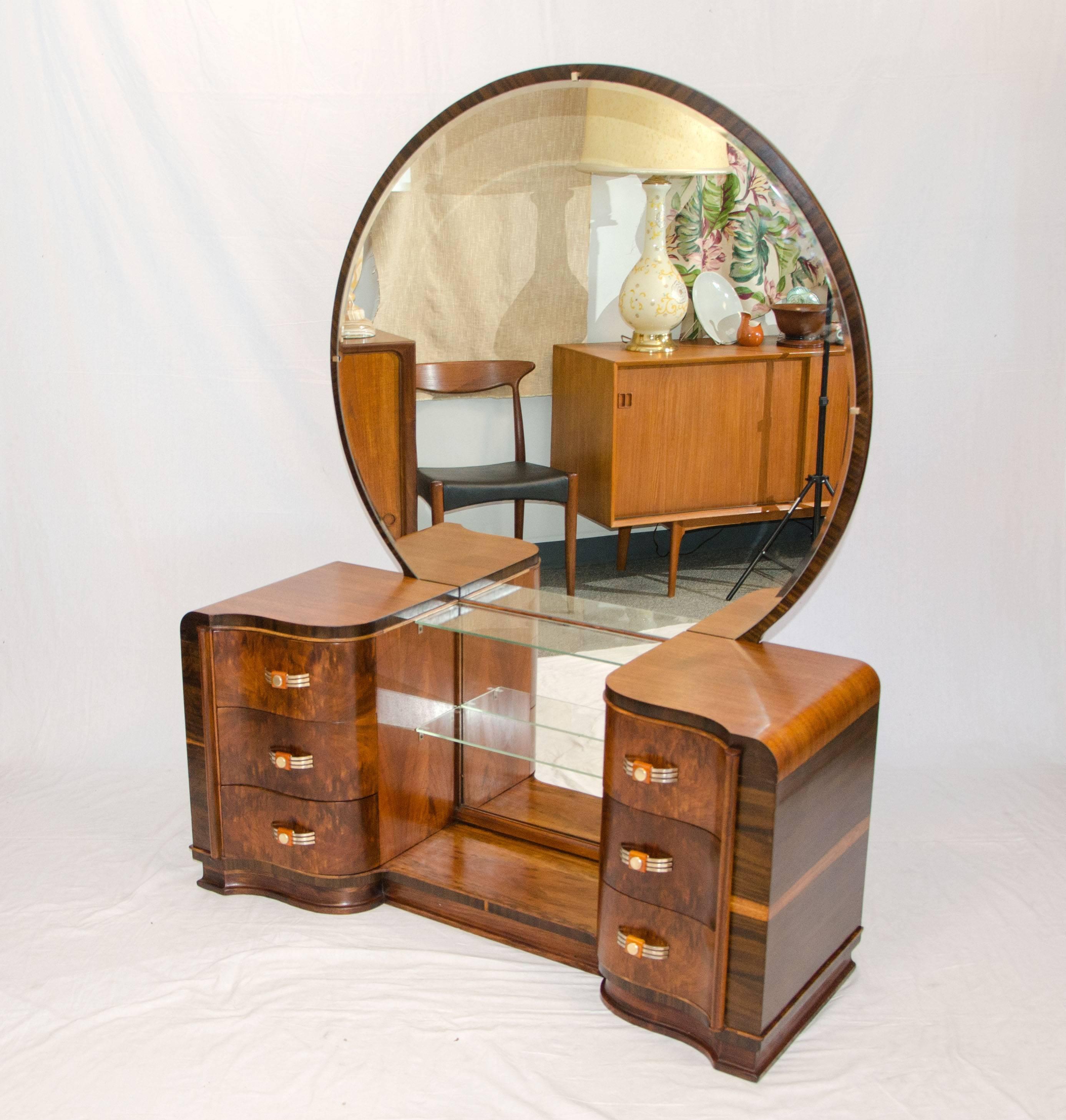 Curvaceous Art Deco walnut vanity with mirror and two banks of drawers that curve into the center with a half serpentine shape. The drawer fronts have book-matched burl walnut grain patterns, the vanity sides also display beautiful grain patterns.
