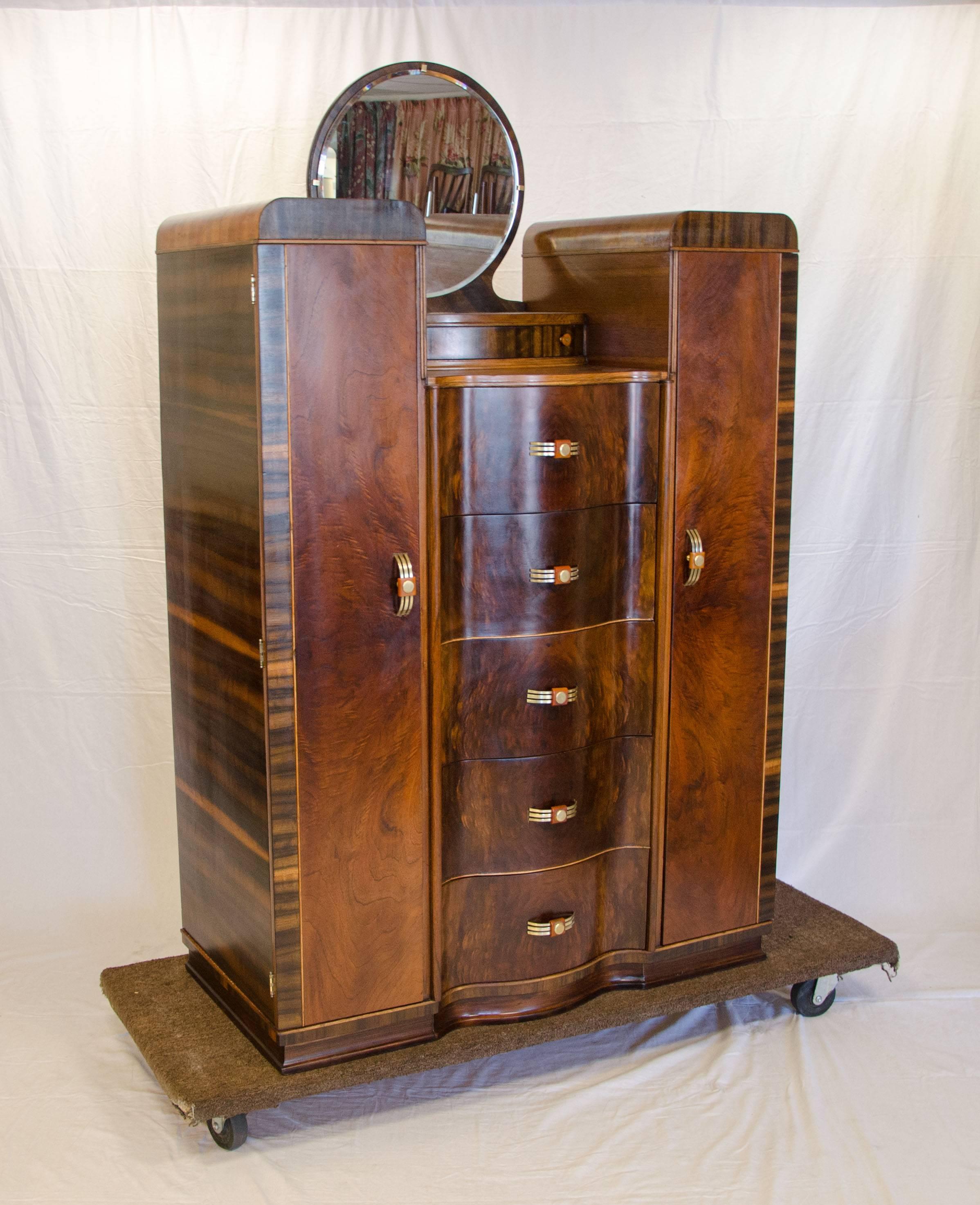 Curvaceous walnut Art Deco dresser or chifferobe with serpentine drawer fronts. The two side cabinets are cedar lined, they retain a bar for hanging clothes but we also outfitted both cabinets with adjustable shelves. Below the mirror there is a