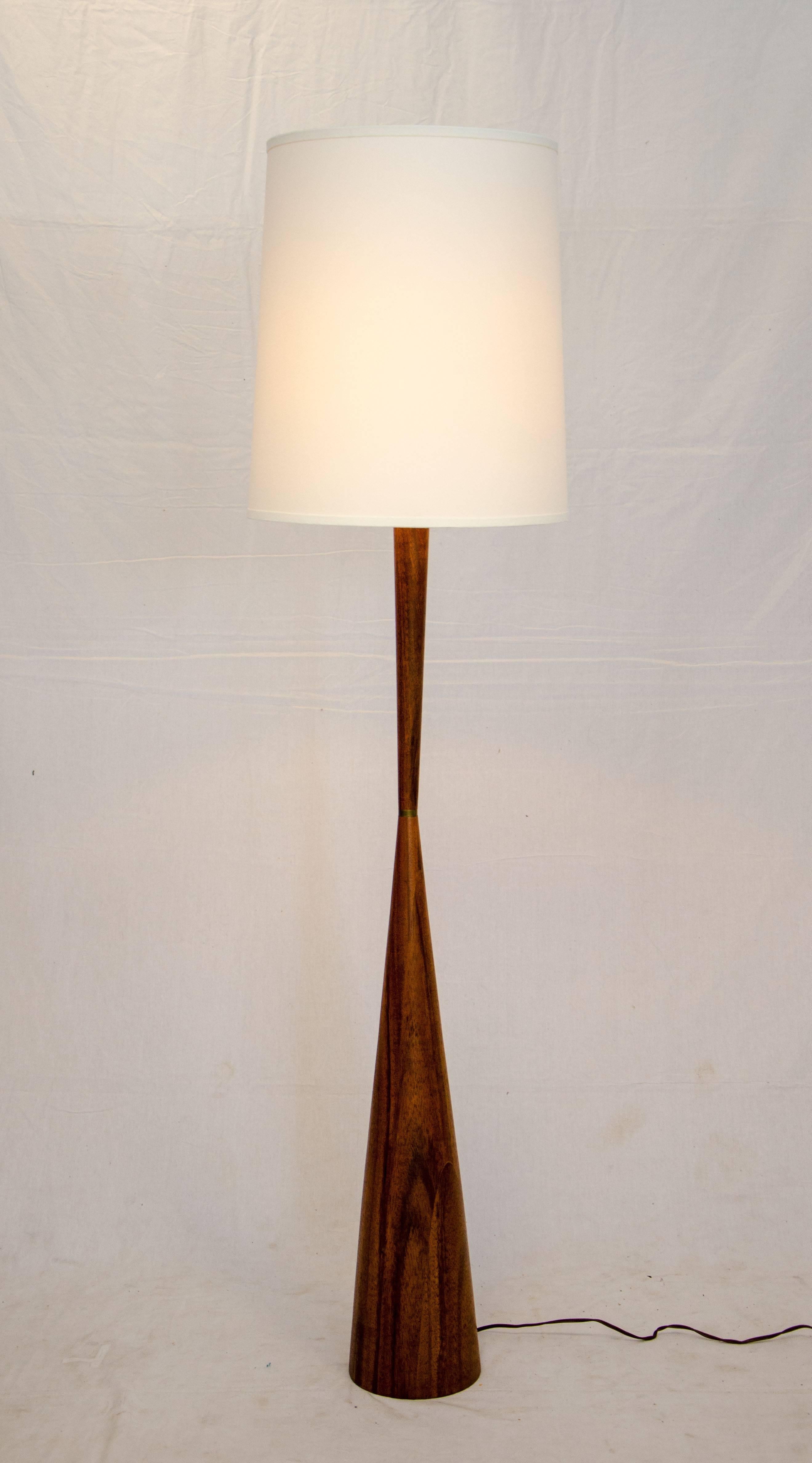 Very nice Mid-Century mahogany floor lamp. The base is cone shaped and tapers to a thinner centre with a brass accent, the taper then widens a bit as it goes up to the socket.
The shade is 18