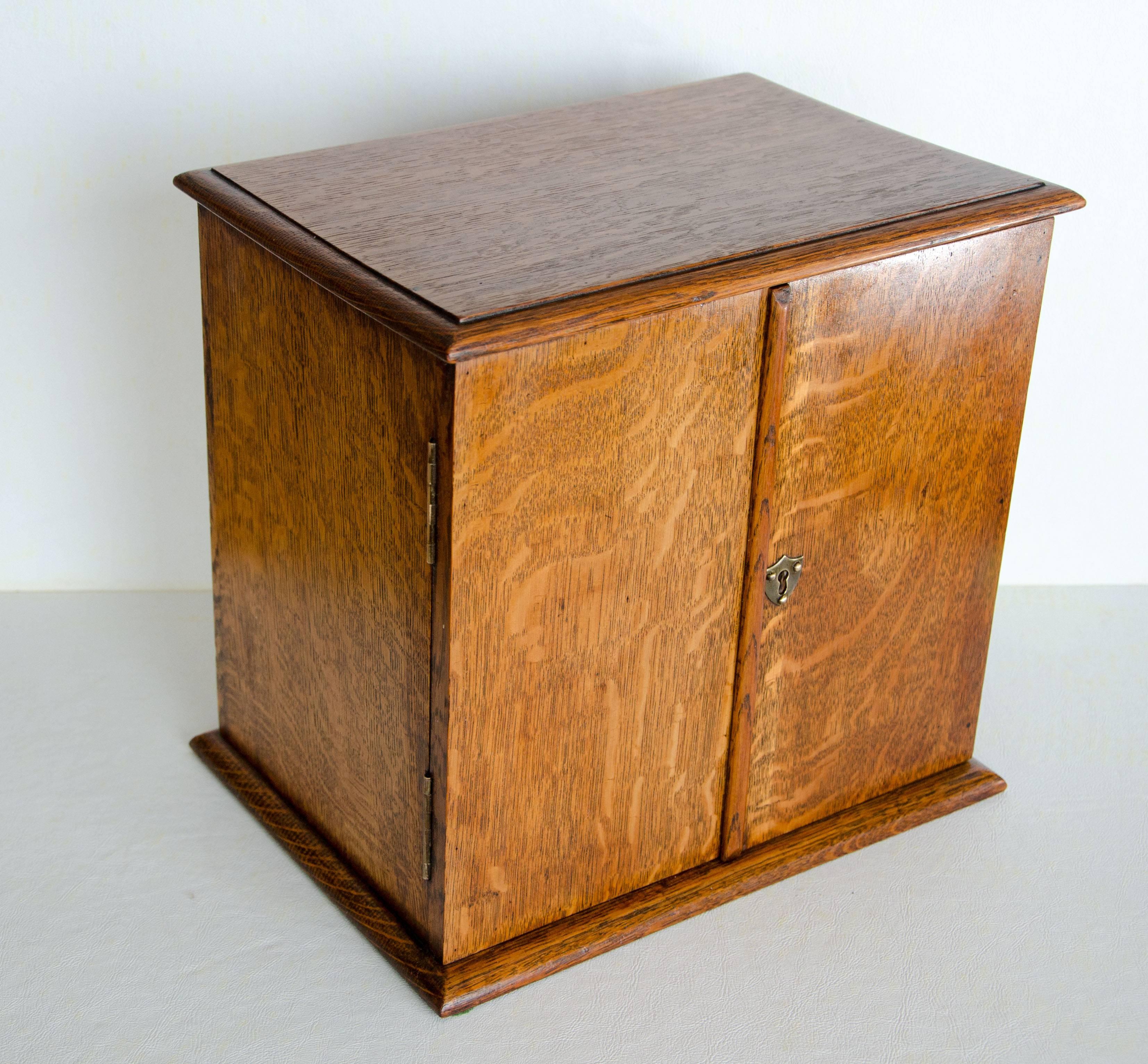  Very nice turn of the century antique quarter sawn oak smoker’s cabinet. The right-hand door has space for pipe storage and has an open storage space behind it. The left-hand door has three small drawers with three filigreed brass pulls behind it.