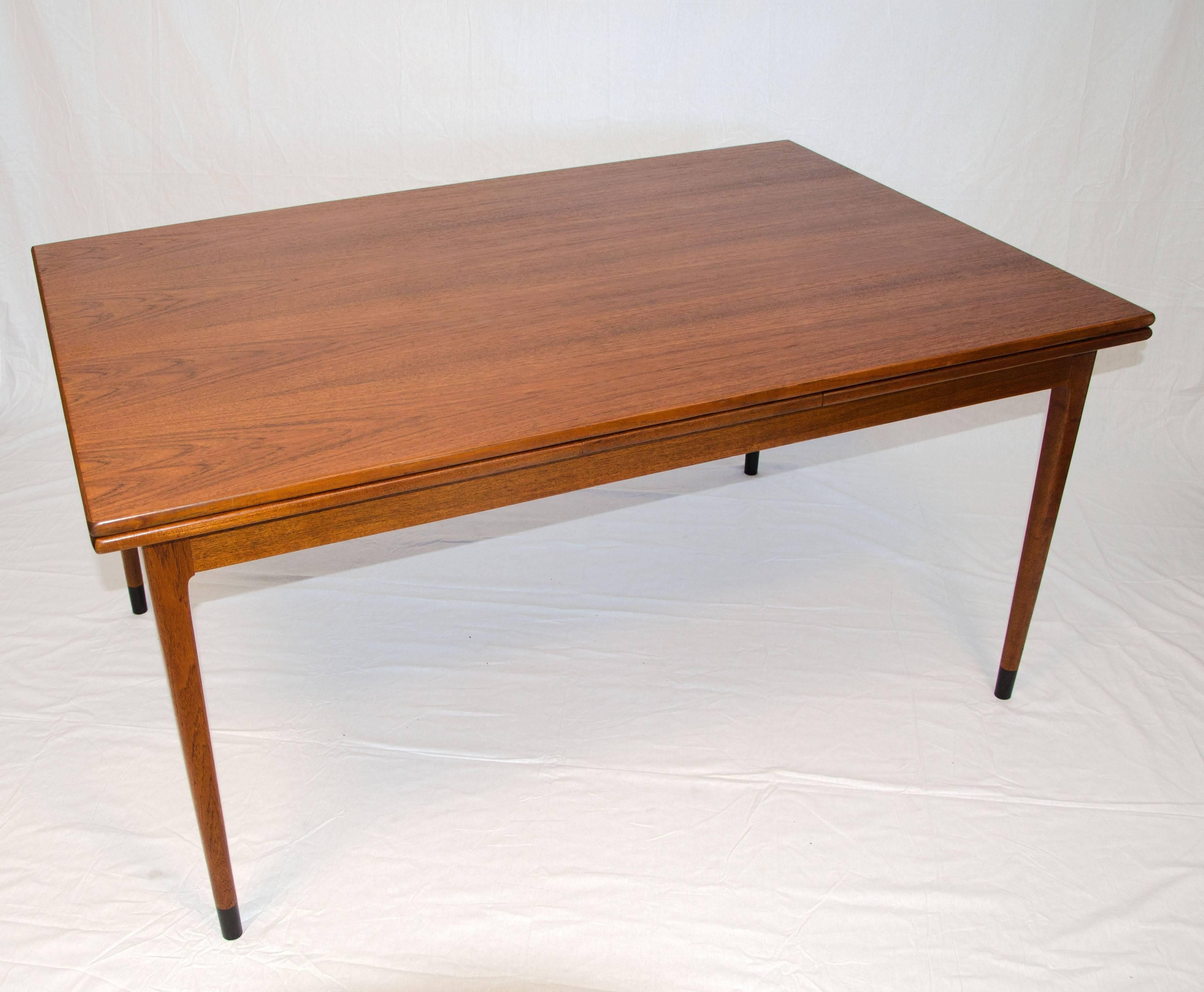 Very nice quality Danish teak dining table with two leaf extensions that slide out at both ends. The table top is supported by rounded tapered legs accented by a 2 3/4