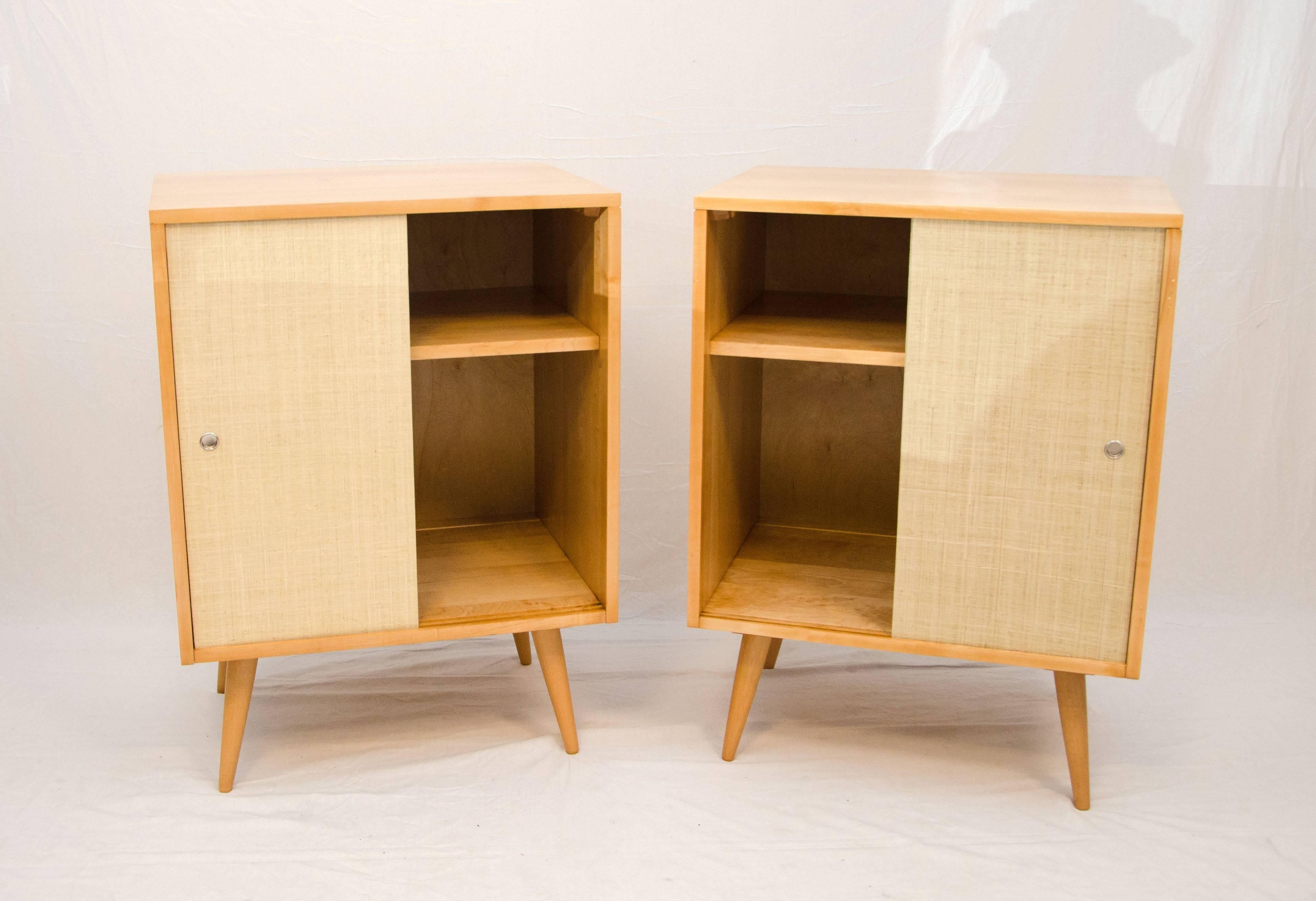 Nice pair of cabinets designed by Paul McCobb. One cabinet has evidence of previous doors that were attached by screws. Matching sliding doors with vintage grasscloth paper were made.