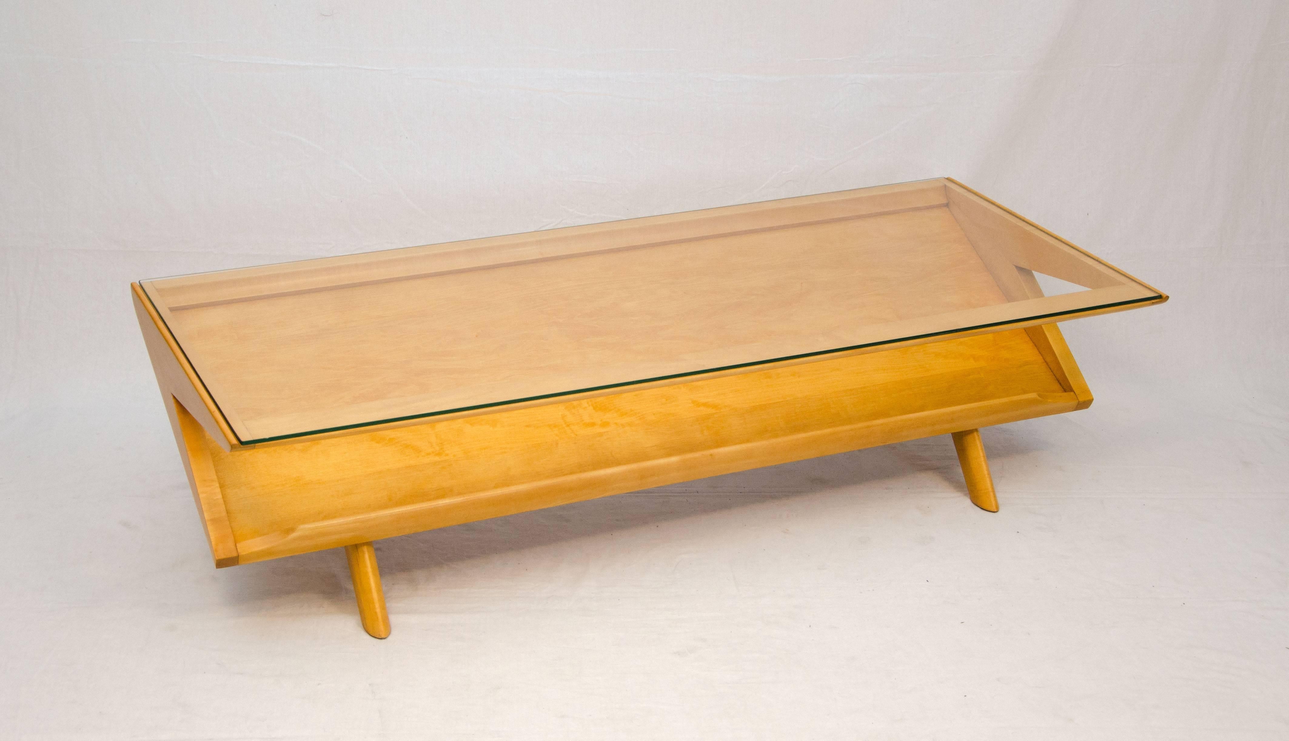Iconic magazine coffee table designed by John Keal and manufactured by Brown Saltman Co. The glass top allows viewing of books or magazines displayed on the angled shelf. Retains the Brown Saltman painters palette company decal.
