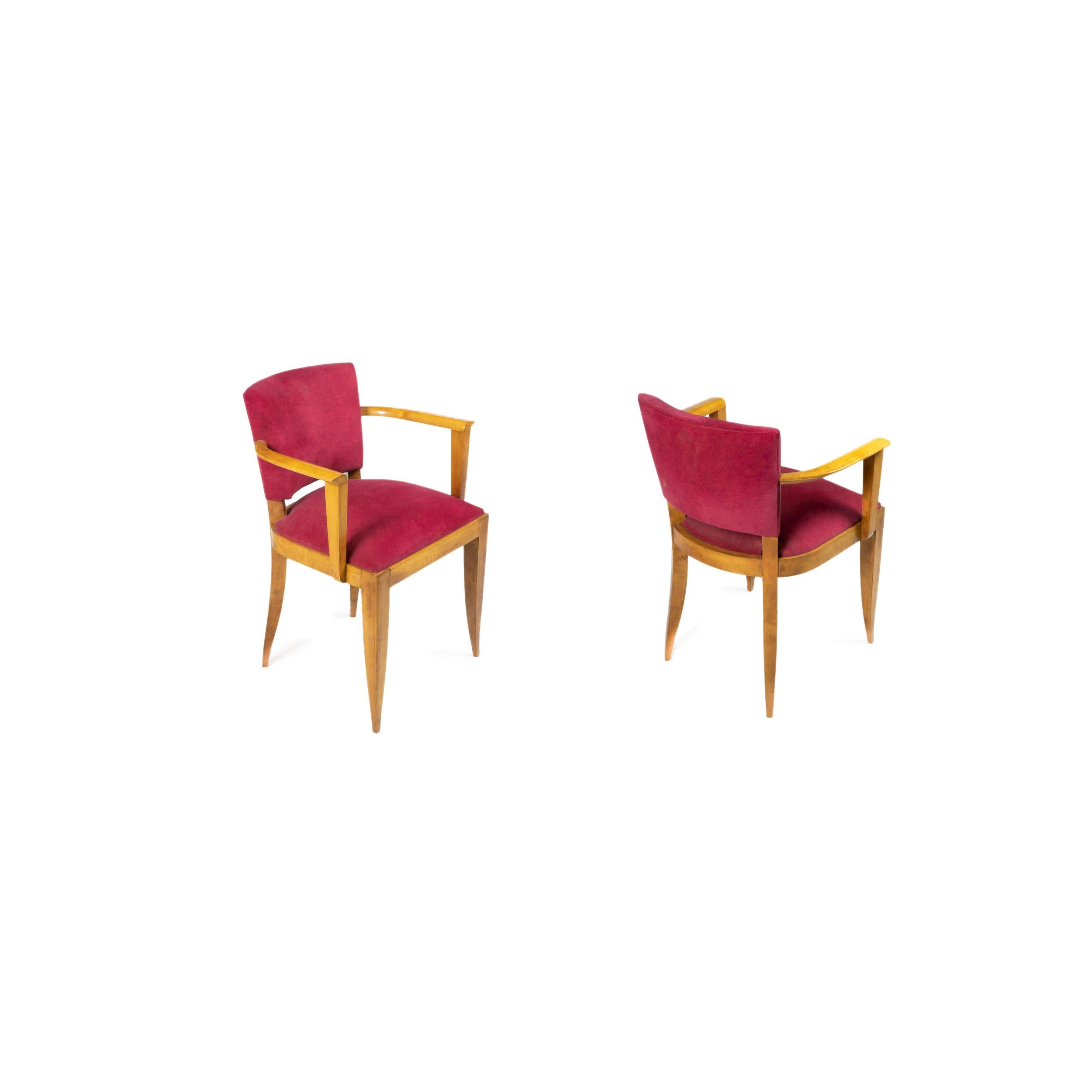 Una coppia di due eleganti sedie a ponte Art Déco con struttura in legno chiaro e rivestimento in velluto color ciliegio.

La consistenza morbida e vellutata del tessuto esalta il comfort e la raffinatezza delle sedie.

Sia il legno che la