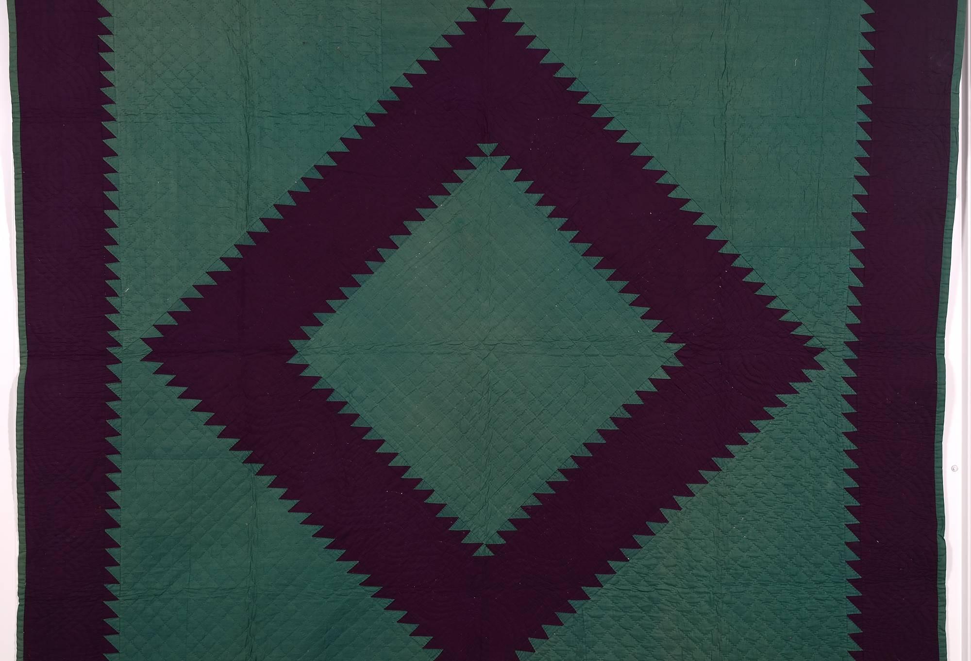 This stunning Mennonite sawtooth diamond quilt is made with a beautiful combination of two rich colors. The darker is an eggplant purple, although it may not appear that way on all monitors. 
It is made of fine wool with a calico cotton backing.