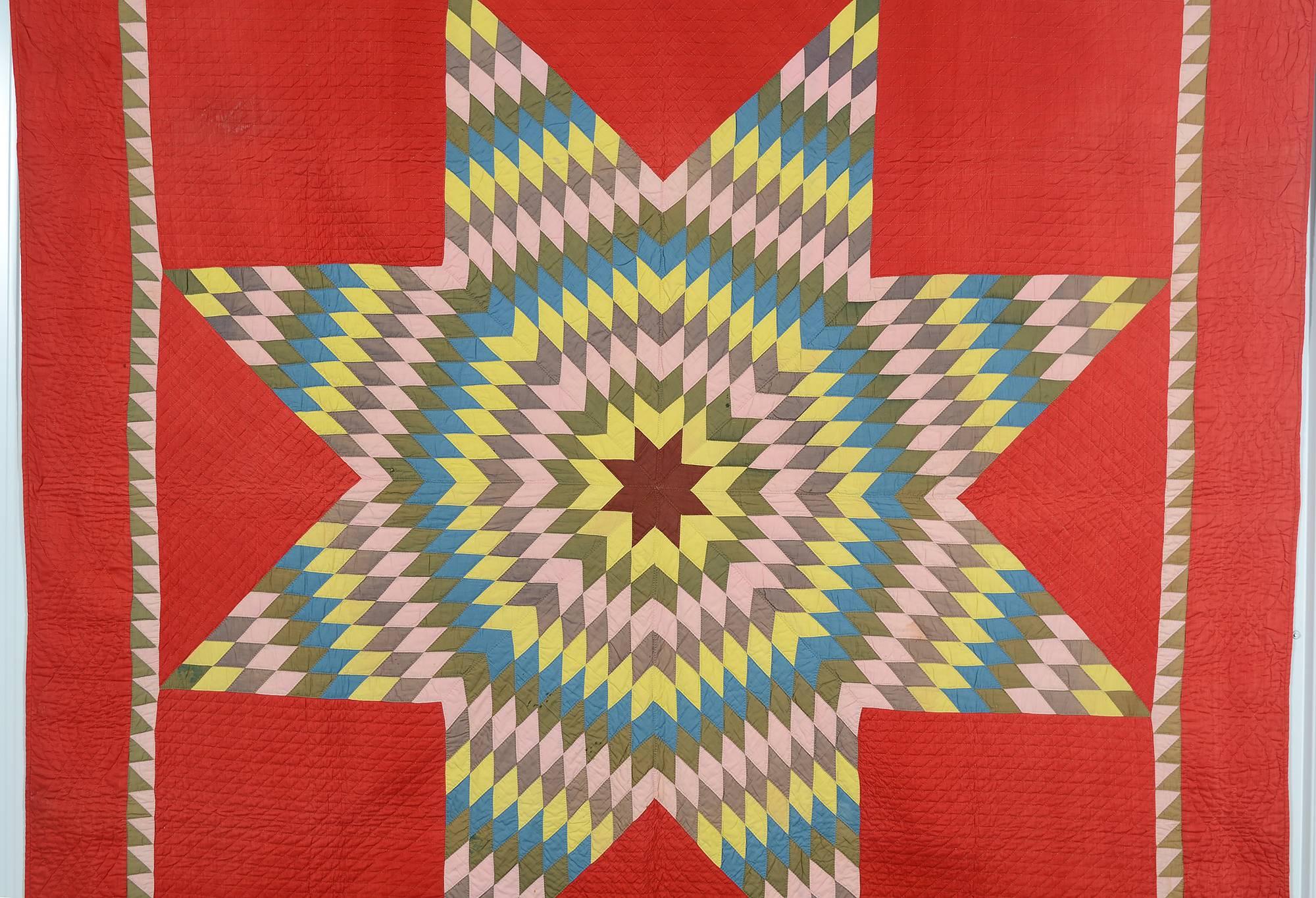 This Lone Star is beautifully offset on a fire red background. The soft colors of the star contrast well with the very strong background. The brown used only for the center star makes a great focus. The body of the quilt is stitched with a pattern