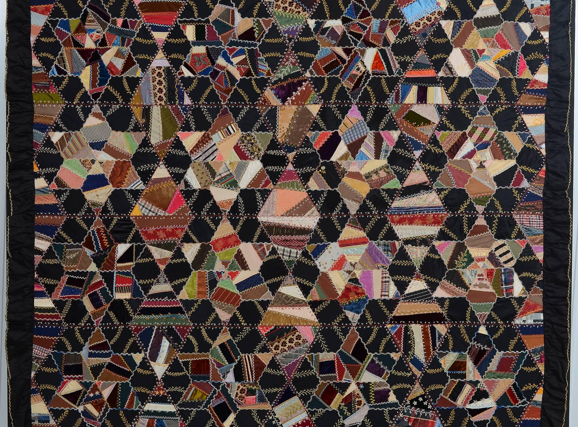 This elaborate Victorian quilt forms several different patterns. Primary is the tumbling blocks coordinating with stars and diamonds. The irregularly shaped pieces making up these patterns are highlighted with contrasting color embroidery. The quilt