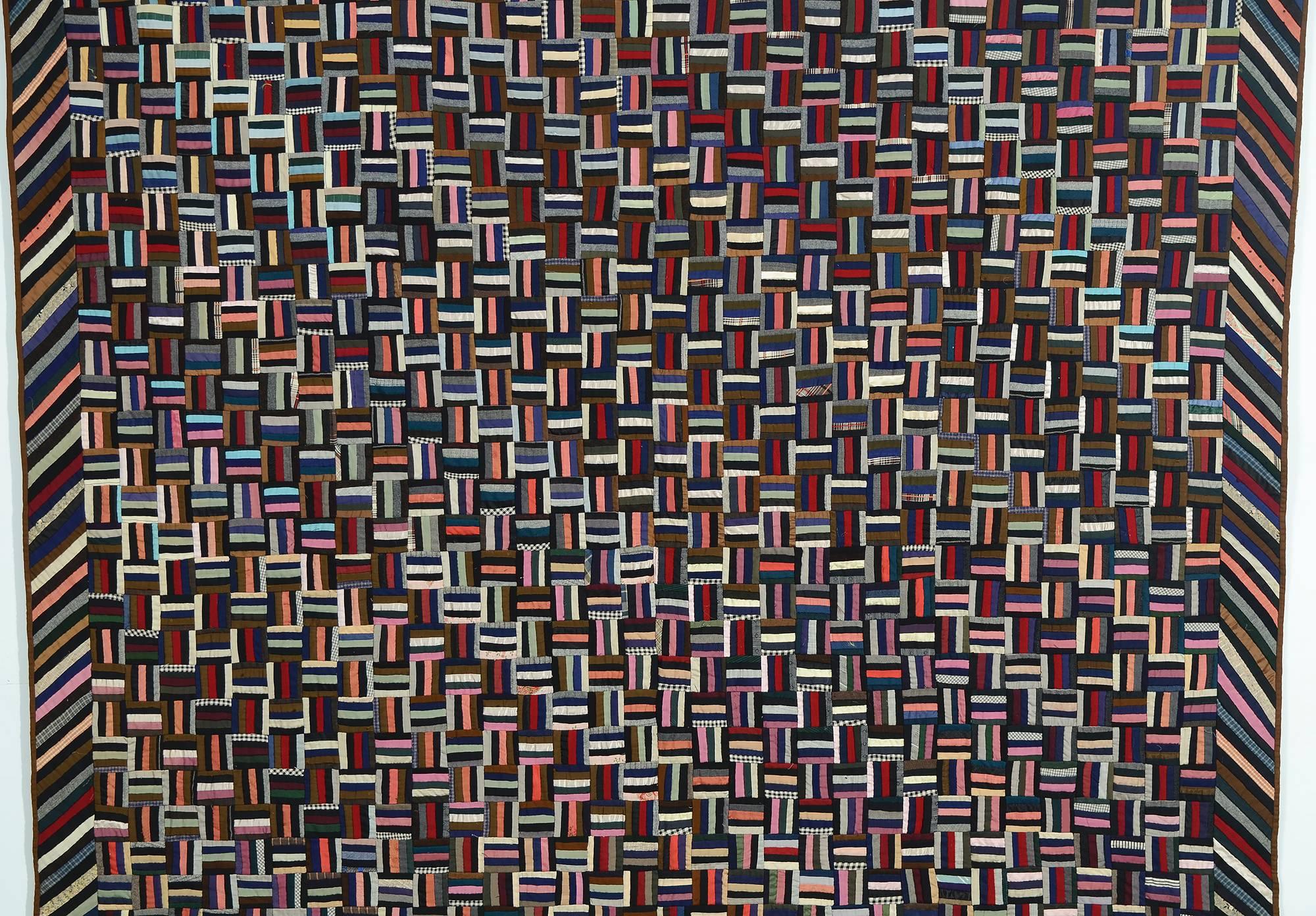 This Fence Rail Log Cabin quilt has an equally dominant secondary pattern. The use of color provides a diagonal design of Straight Furrows as well. 
The small-scale of the blocks makes for very intense patterning. Each block is about two inches to