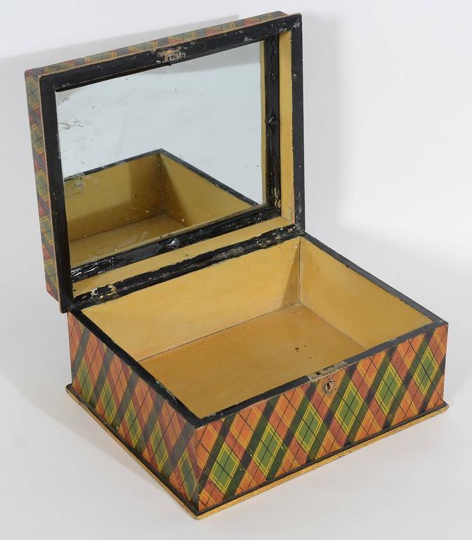 This colorful tartan plaid box is hand decorated with shades of green; orange; red and yellow. It retains the original paint in very good condition. A newspaper under the interior mirror is dated 1871. Probably Pennsylvania origin.