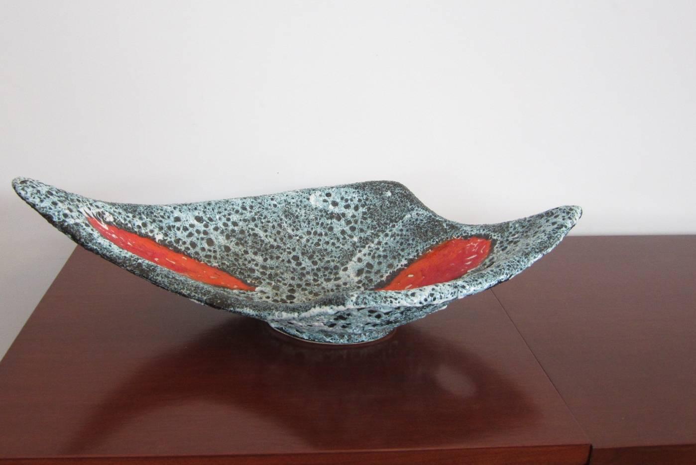 Handmade pottery bowl with lava finish and patches of orange glaze design on the interior along with a cut-out design. Beautifully flared and swooped.