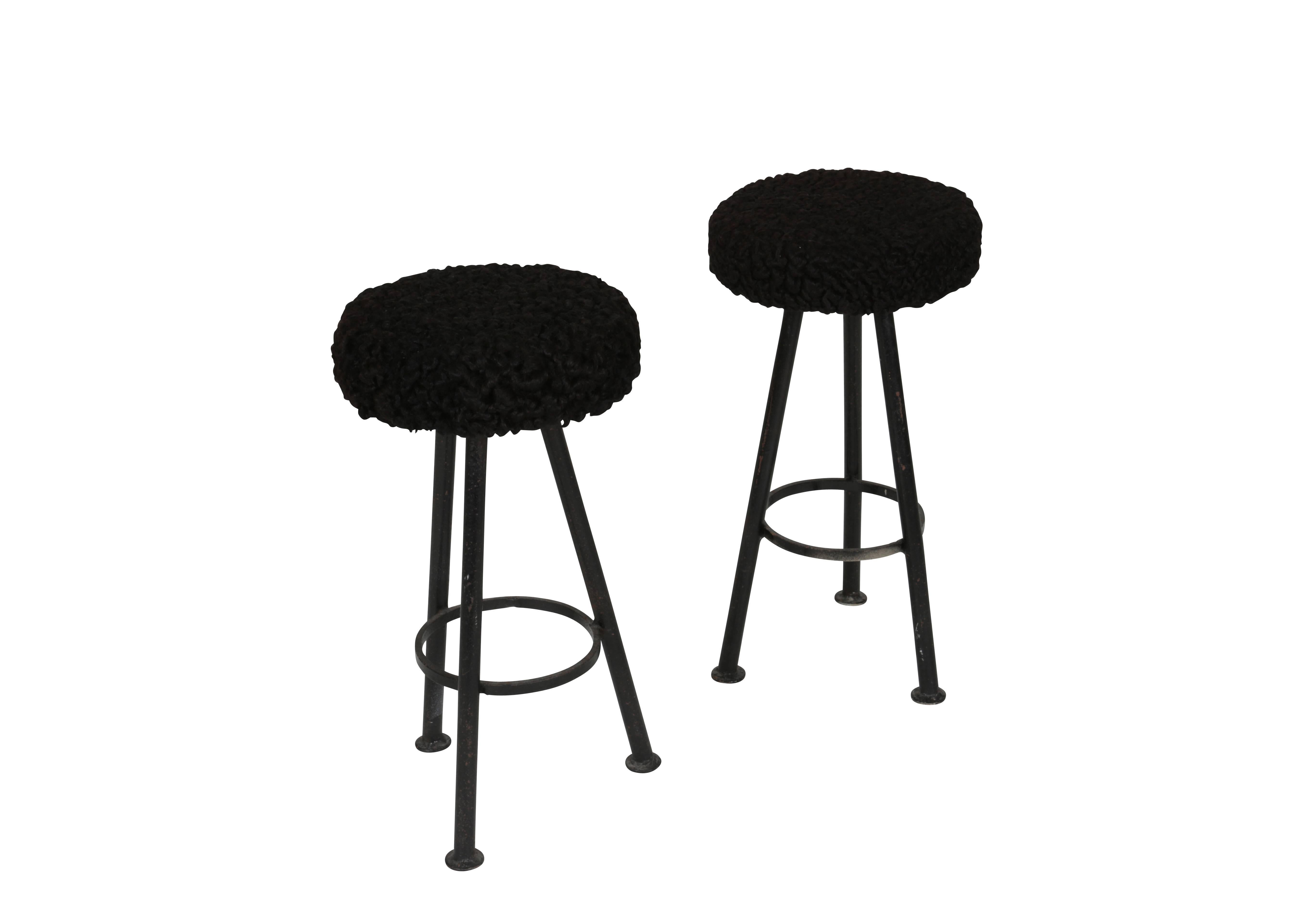 Pair of low-profile three legged black iron an black Persian lambs wool stools.