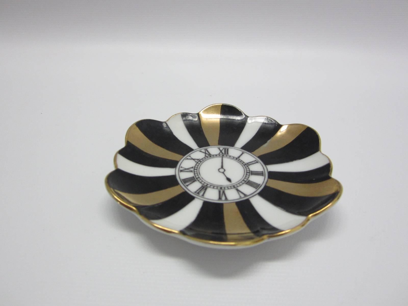 Porcelain trinket dish made expressly for Bergdorf Goodman New York City. Roman numeral clock design surrounded by black, gold and white stripes and scalloped edges.