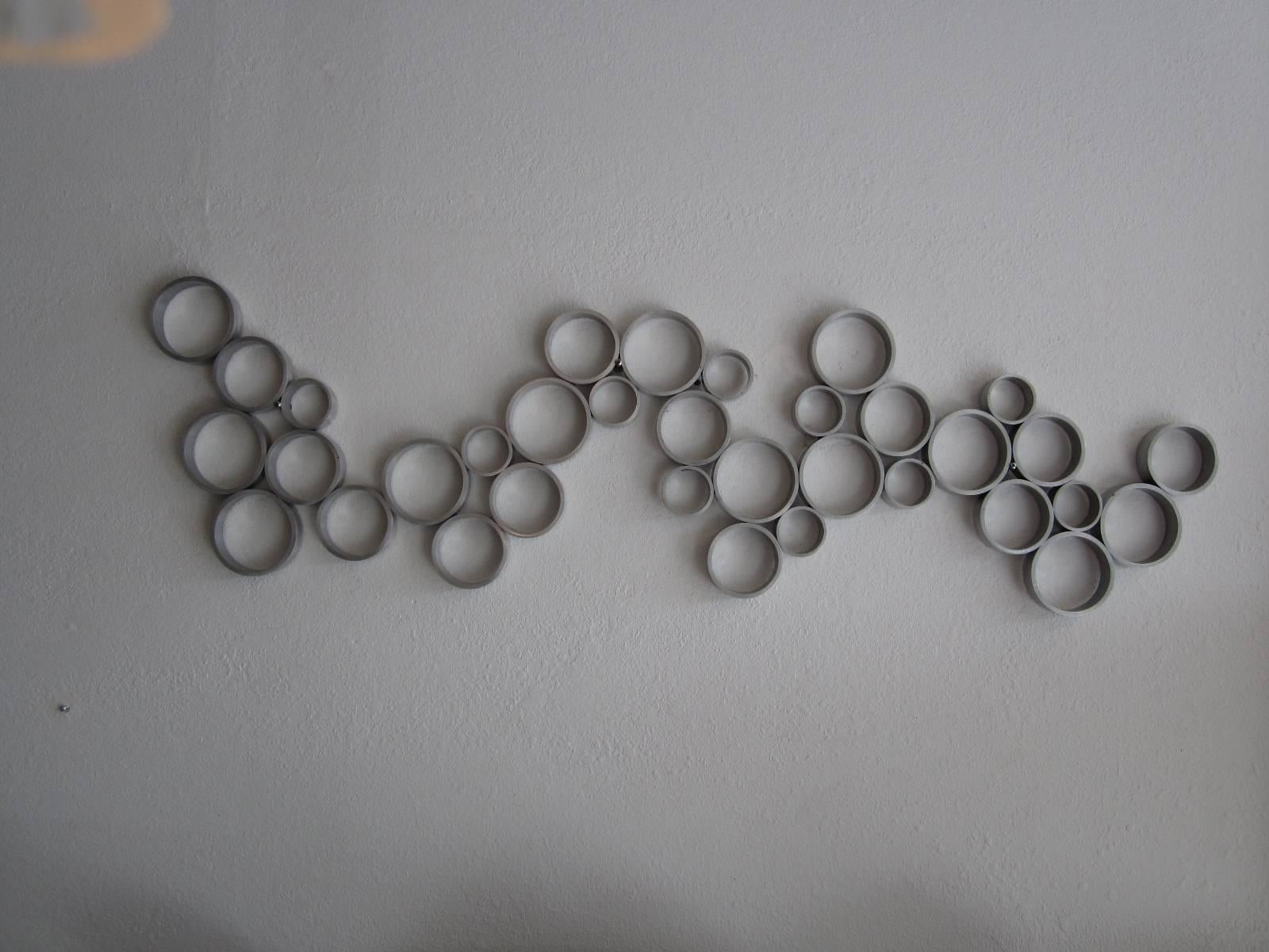 Welded wall sculpture of varying sized circles in aluminum. Mounting horizontally as shown or vertically or angled.