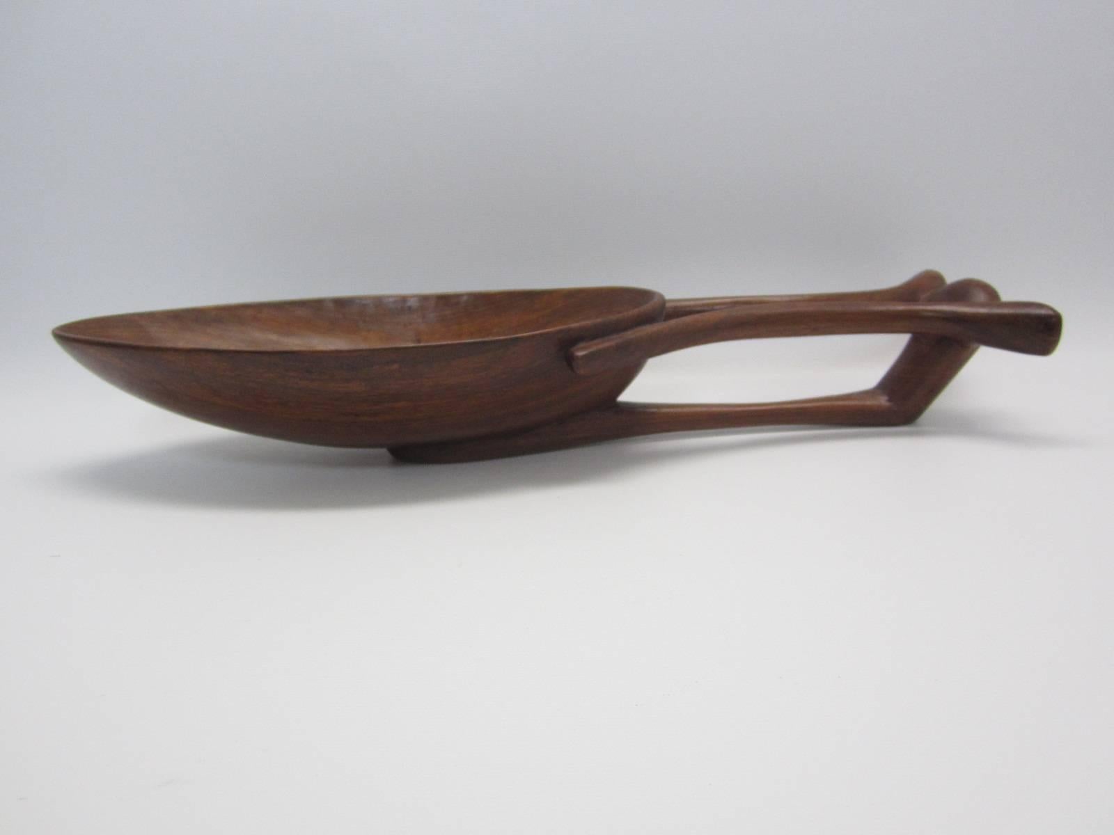 Beautifully carved wood bowl with carved three-part handle which extends underneath the bowl providing stability as a base. Lovely patina and proportion with almond-shaped bowl. Bowl is both decorative and utilitarian at once.