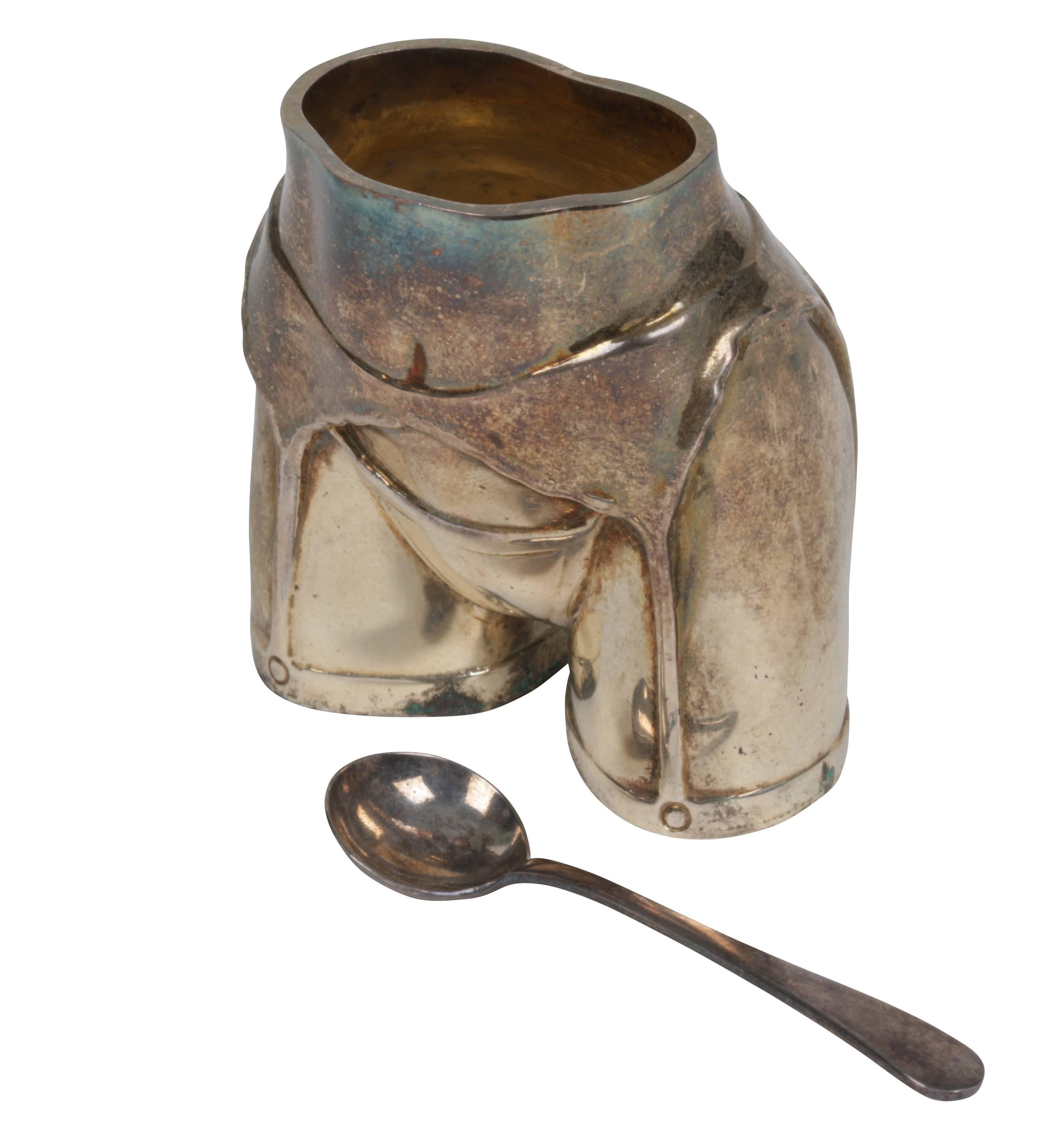 Handcrafted silver plate vessel/toothpick holder/salt cellar with accompanying silver plate spoon. The hallmarked vessel erotically depicts the human buttocks and thighs wearing a garter and lingerie and is stamped Fannell and is hallmarked. The