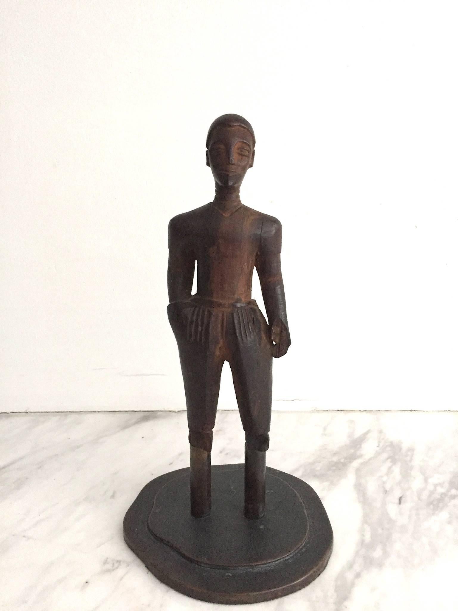 Hand-carved hardwood male figure on hand-made amorphous bronze base. Fantastic male figure with one hand in pocket and pleated trousers. The feet are removed where the figure is attached to the bronze base. Natural wear gives warmth and beauty to