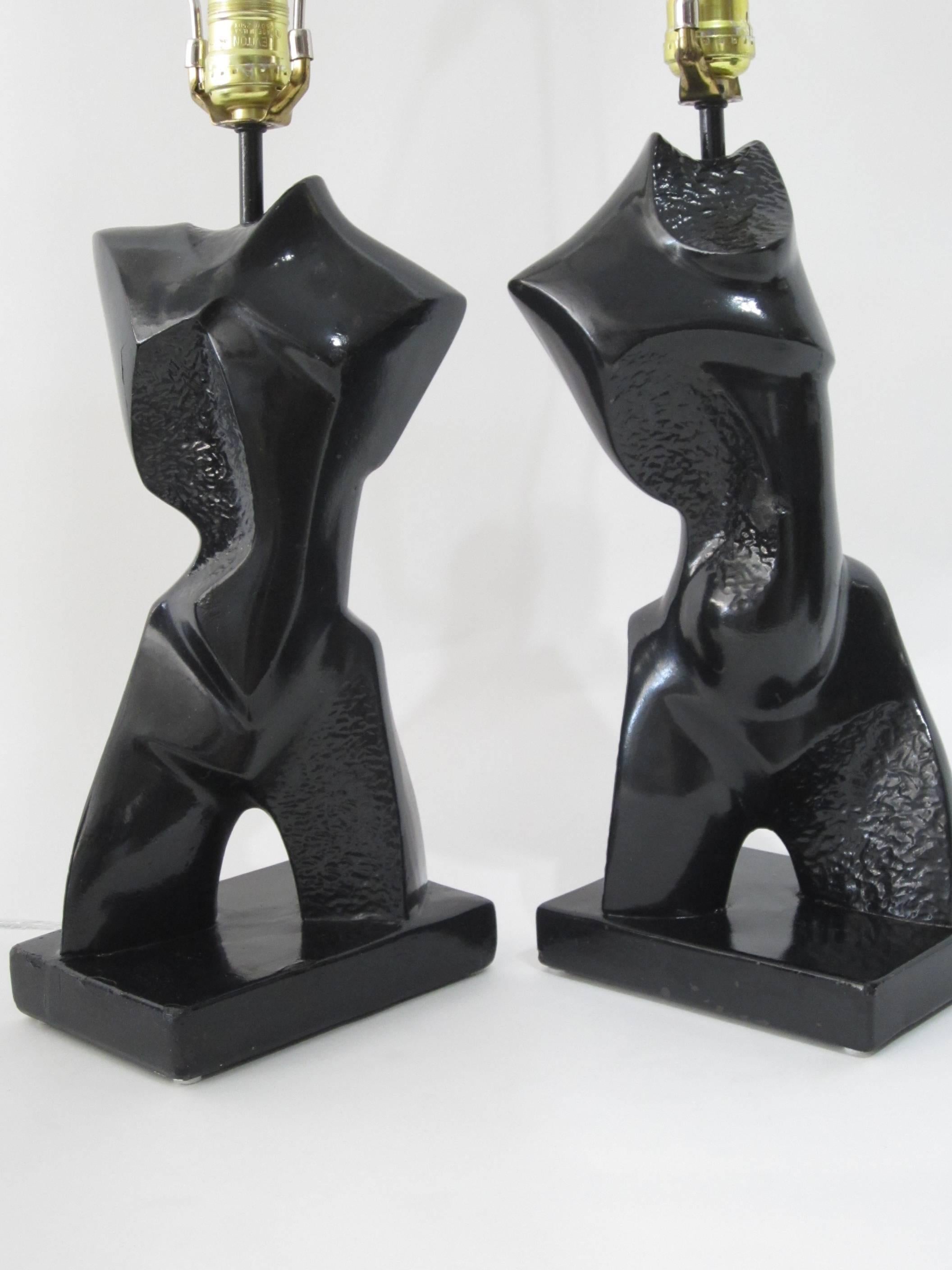 Great pair of chalk-plaster black painted abstract lamps by Heifetz.
Height to sockets is 16 inches. Age appropriate wear to the plaster with touchups to the paint. Sold as a pair with or without the silver-lined black paper shades. 