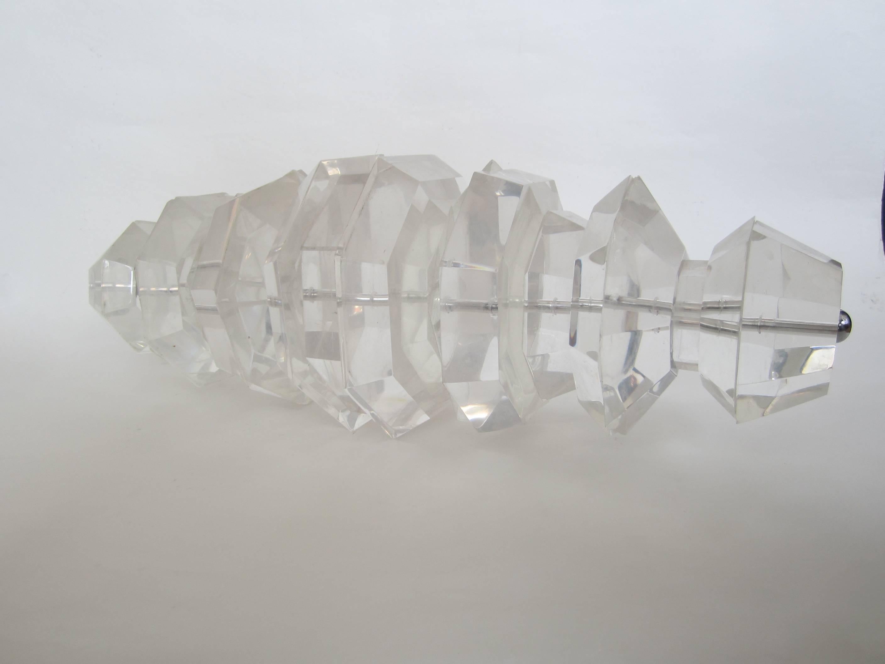 Amazing very large and heavy notched and faceted thick lucite sculpture, signed, found mounted from the ceiling in a New York jewelry store. Has chrome rod running through it holding it together and is capped on each end with a chrome screw cover.