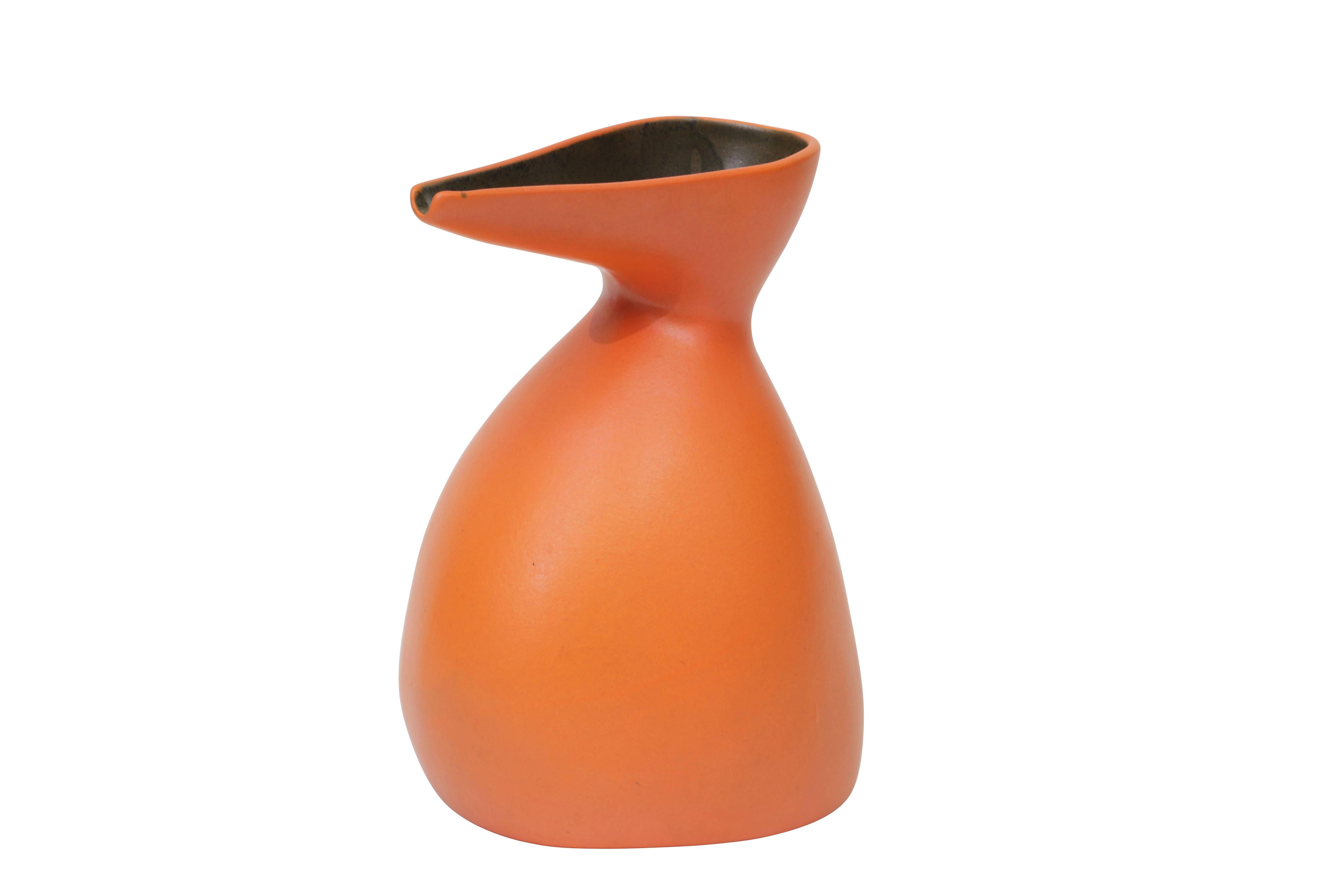 Beautiful ceramic pitcher with rich orange exterior and black interior.
