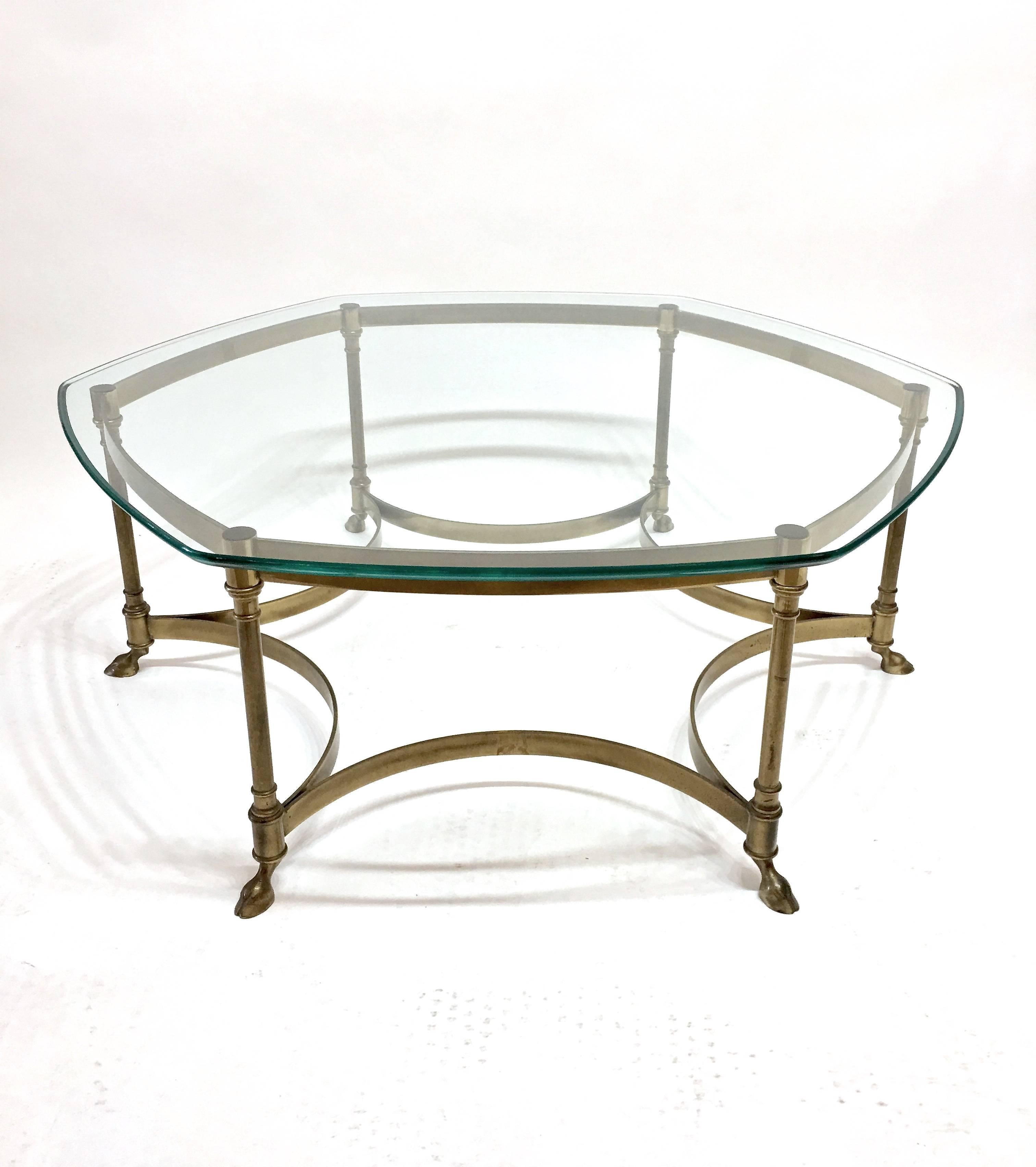 Great brass frame cocktail table by Mastercraft with six legs terminating with hoofed feet. The legs have concave brass stripping on the lower portion of the frame with detail to the tops and bottoms of legs. The glass top is all soft edges