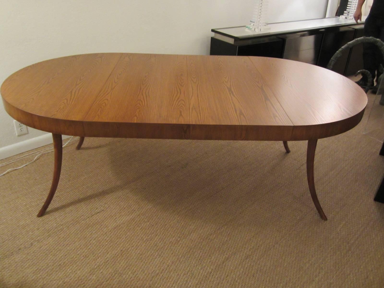 Gorgeous oblong walnut and mahogany dining table with Klismos legs and two leaves as shown in main image. When the leaves are removed, the table is a perfect round, shown in the additional images. Designed for the John Widdicomb Furniture Company in