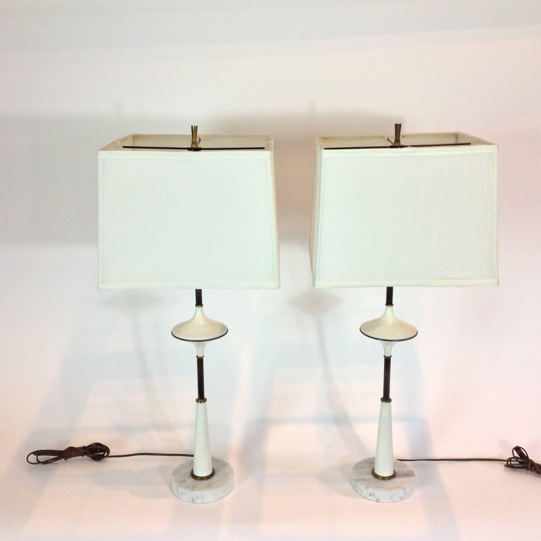 Wonderful pair of black and white enameled metal lamps accented with brass rings and marble bases. Original wiring in working condition. Sold with or without the shades.
Height shown is to top of finials, height to sockets is 19 inches.