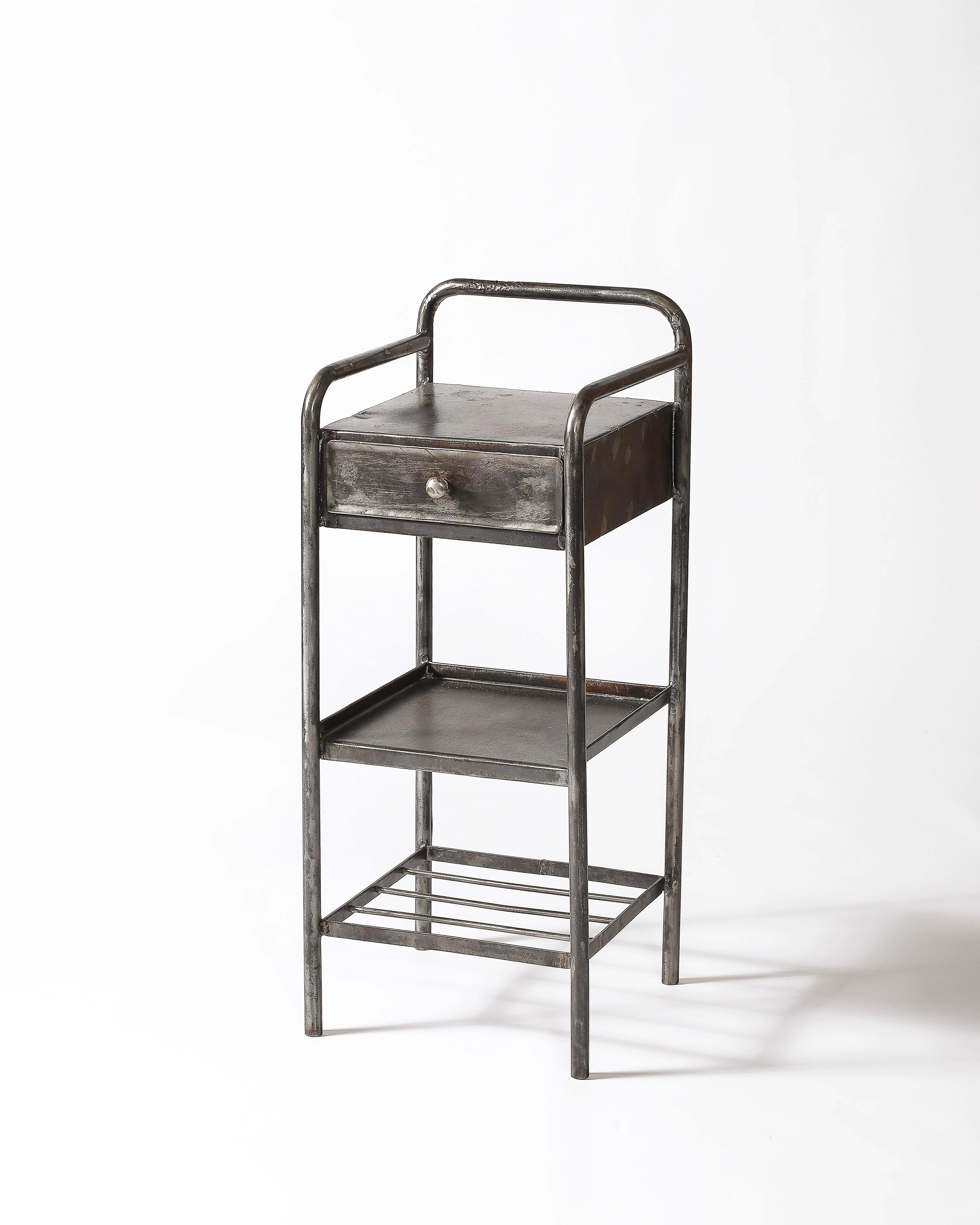 Table d'appoint en acier patiné, avec un tiroir et deux étagères. Peut servir de table de chevet.