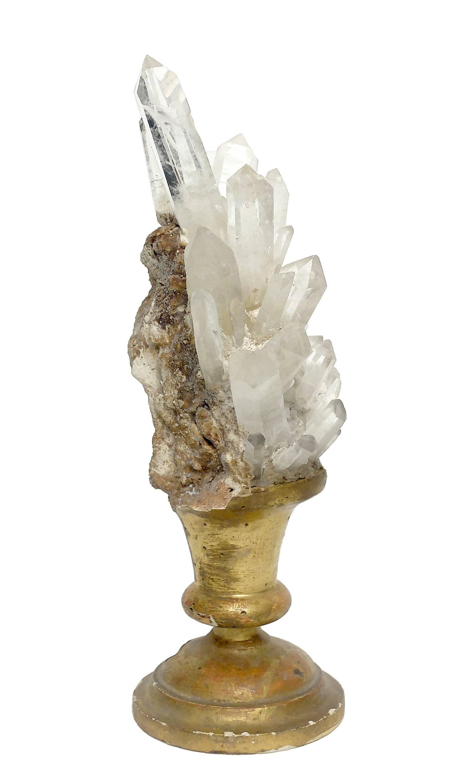 A Naturalia mineral specimen a rock crystals druzes, mounted over an older gold-plated wooden base in a shape of a vase.