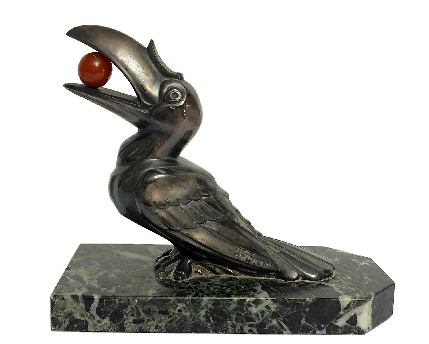 Pair of bookends. Green veined marble with L-shape structure. Over the ‘L’ marble base, two identical white metal sculptures of birds Toucans, with a ball of amber in its beak. Pure Art Deco’, France, circa 1925. Signed H. Moreau.