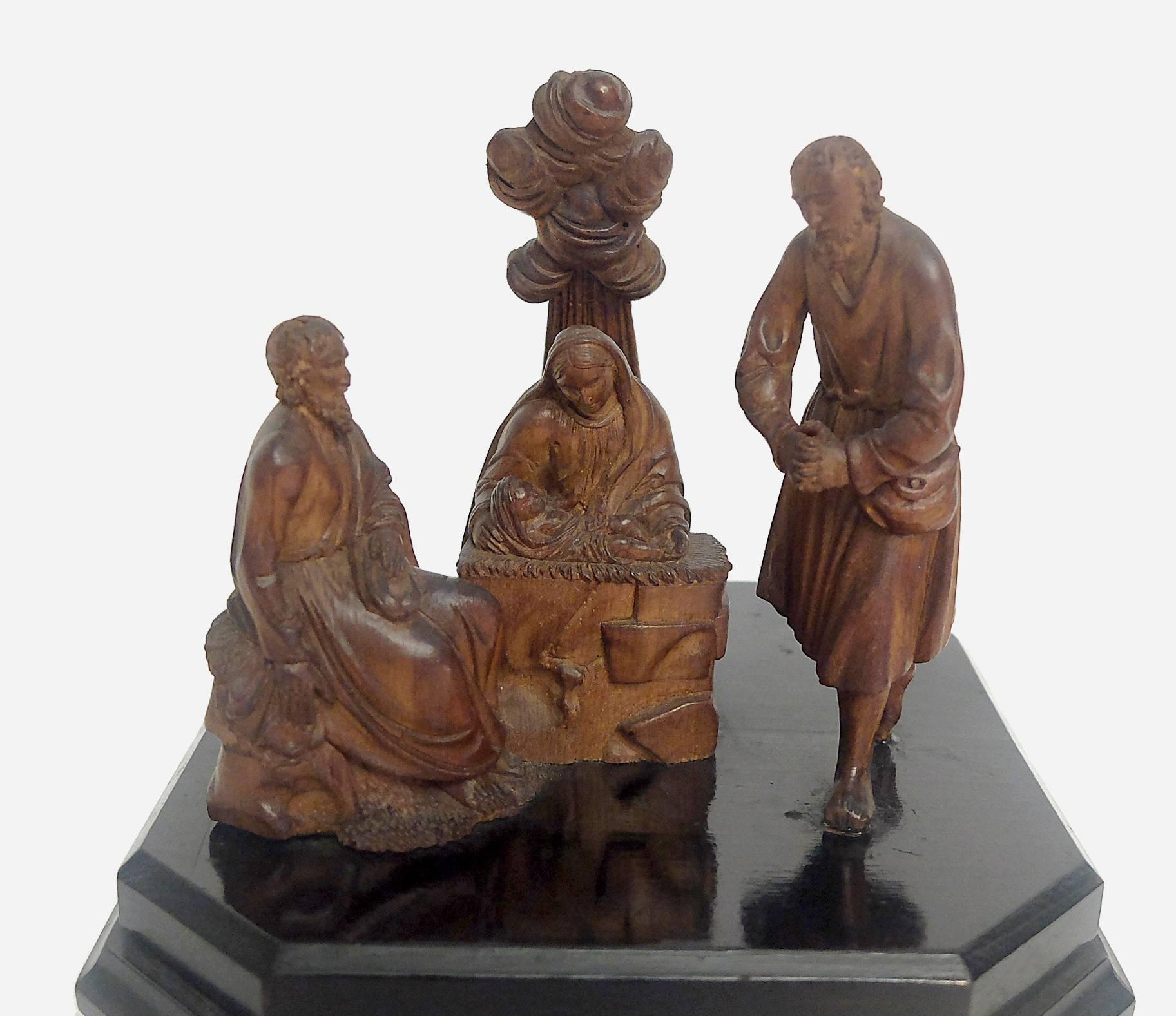Over a wooden base, black colored, with moved profile, stand three extreme miniature figures, with the Holy Mother with the child in the centre. Behind her, the clouds and the rays of God. Perfect sculpting, extremely rich of details, Germany, late