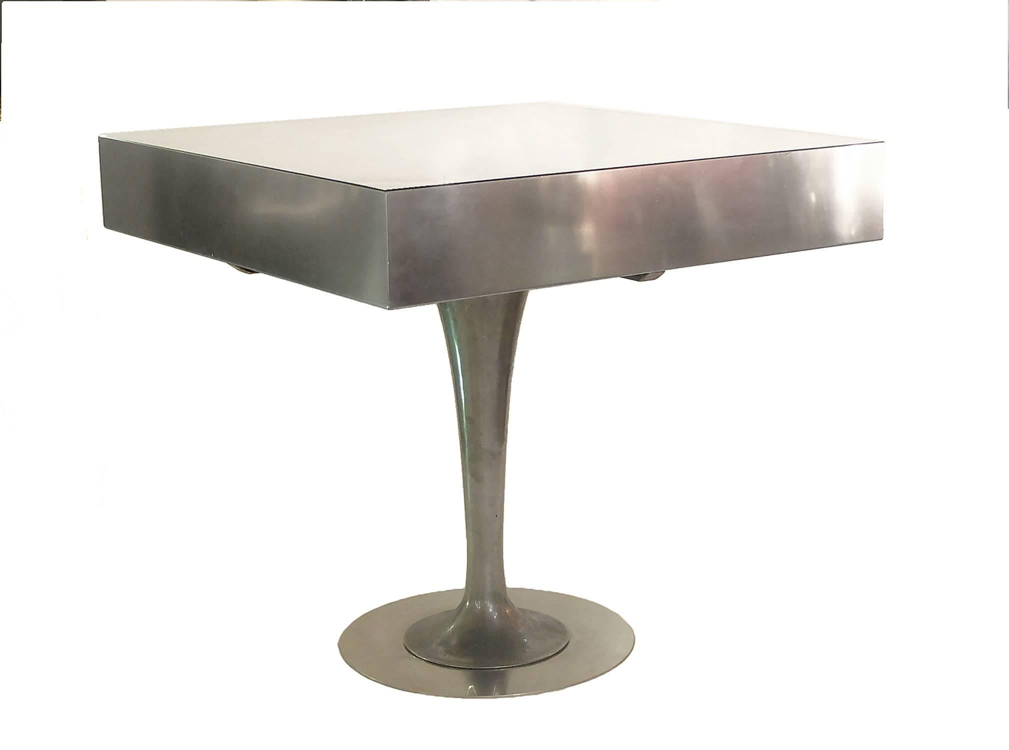 The leg, made out of aluminium, is in the purest American Art Deco.
The round base rise and opens wide to the top. The top is made out of a juxtaposition of cardboard elements, boxed inside an aluminium frame, with glass top.
The entire top is