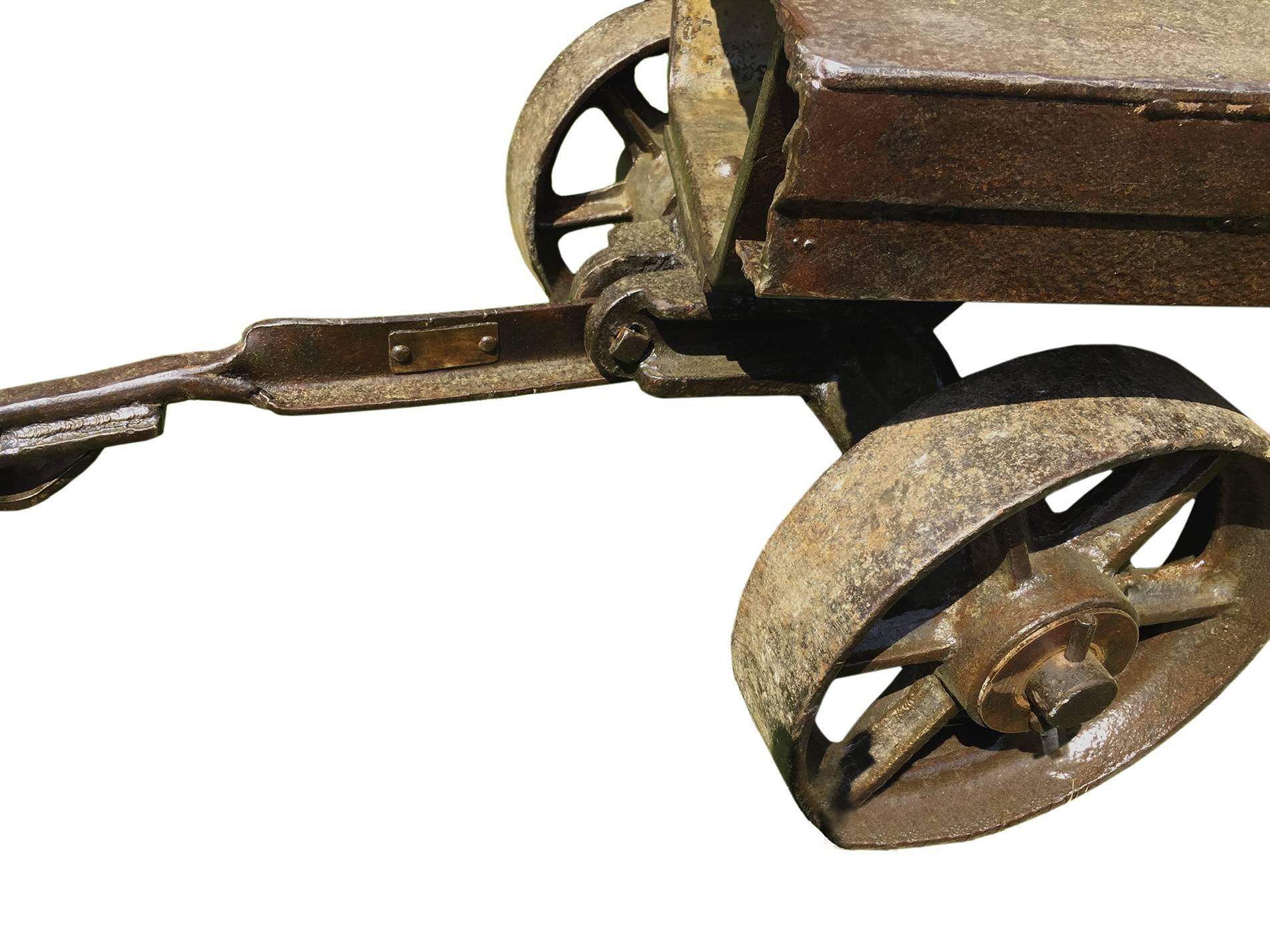 Iron and cast iron industrial wheelbarrows , rectangular shape , with 4 big wheels (11” diameter) and a long handle that allowing the front wheels to rotate . The top shelf has a thickness of 4 “ .