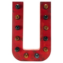 Large red tin letter U illuminated by light bulbs. USA 1930.