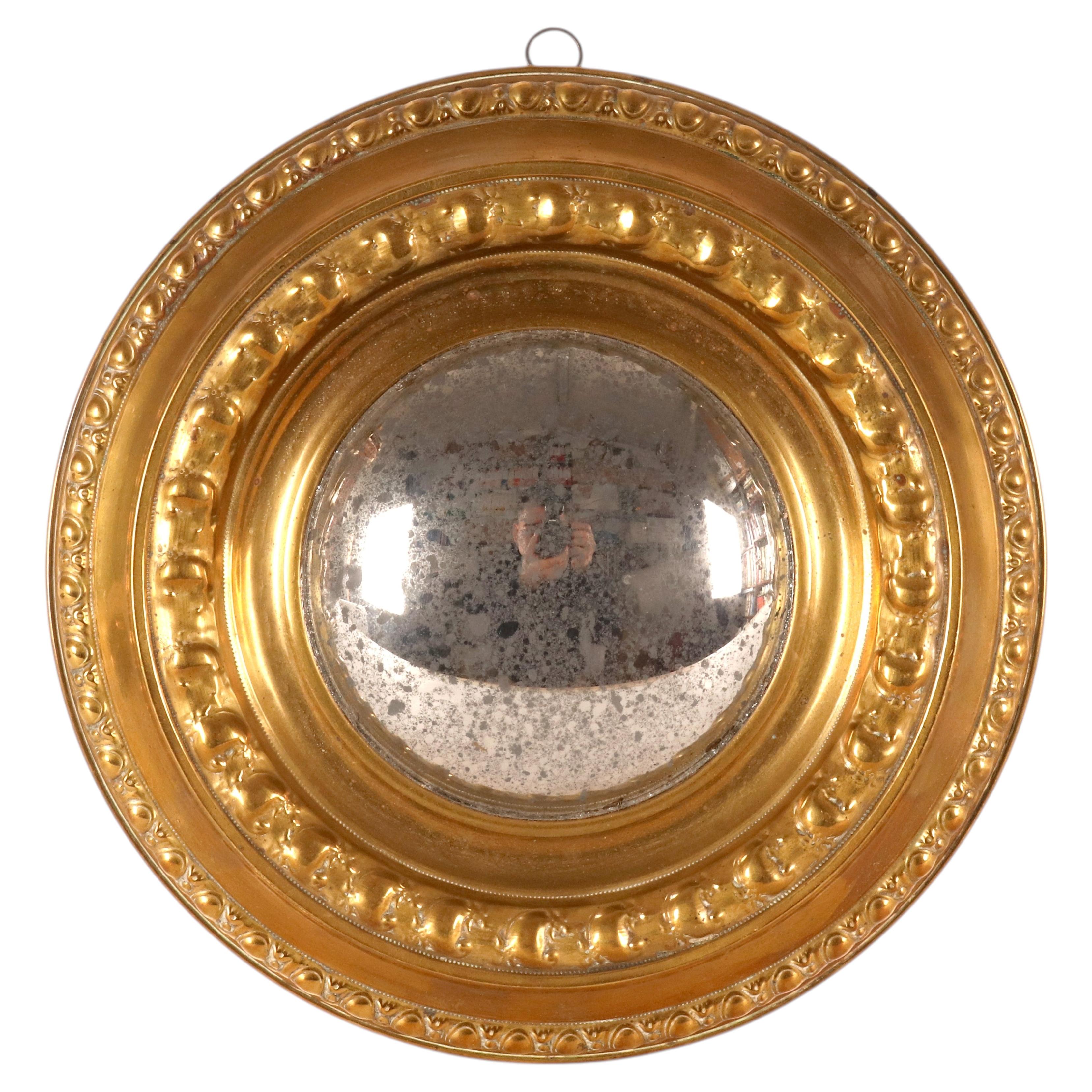 A convex mirror with smooth, embossed brass frame. Italy, circa 1890.