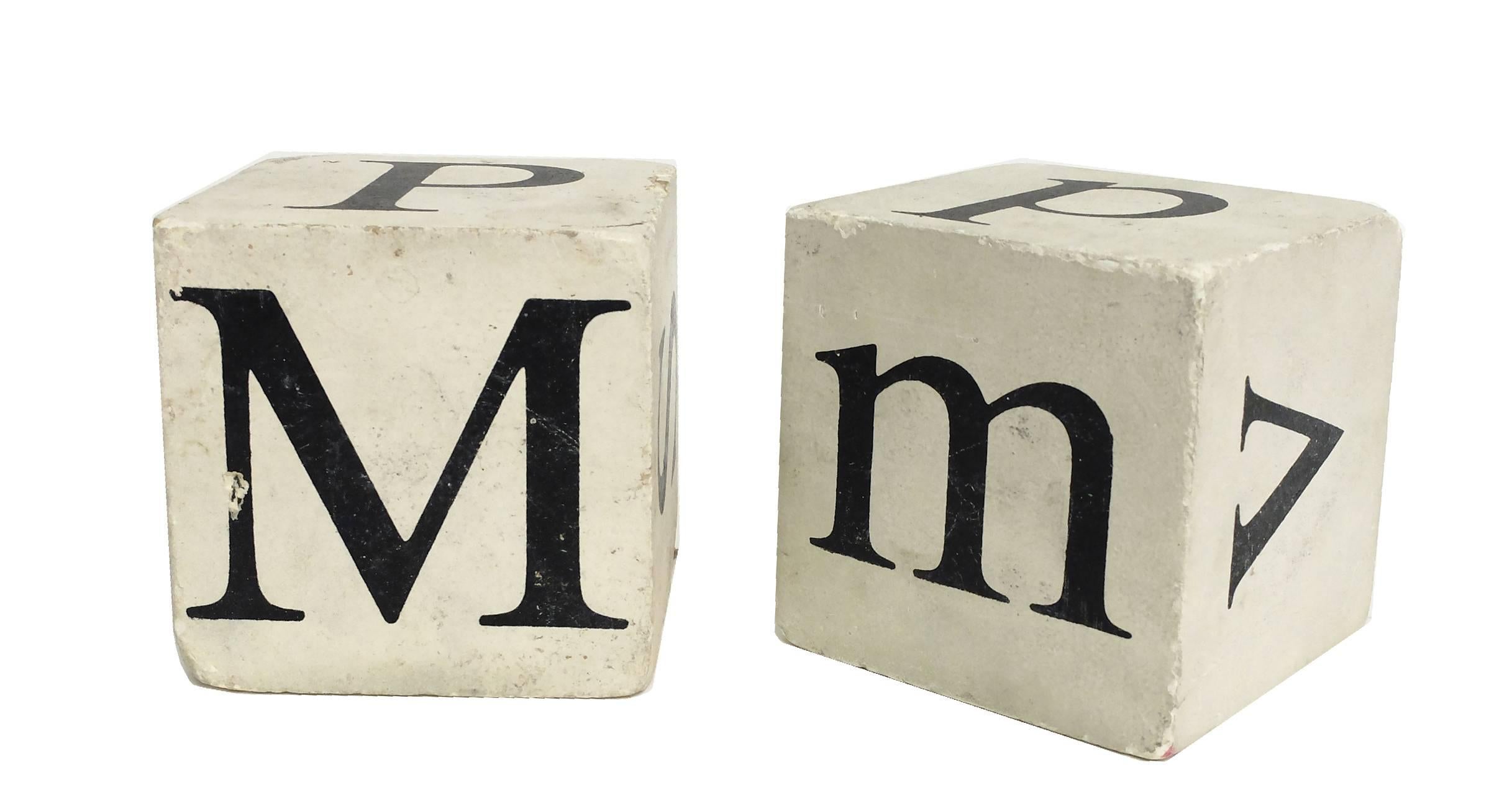Pair of dice made of papier maché and plaster, painted black on white with different black letters in each face of the cube, USA, circa 1900.