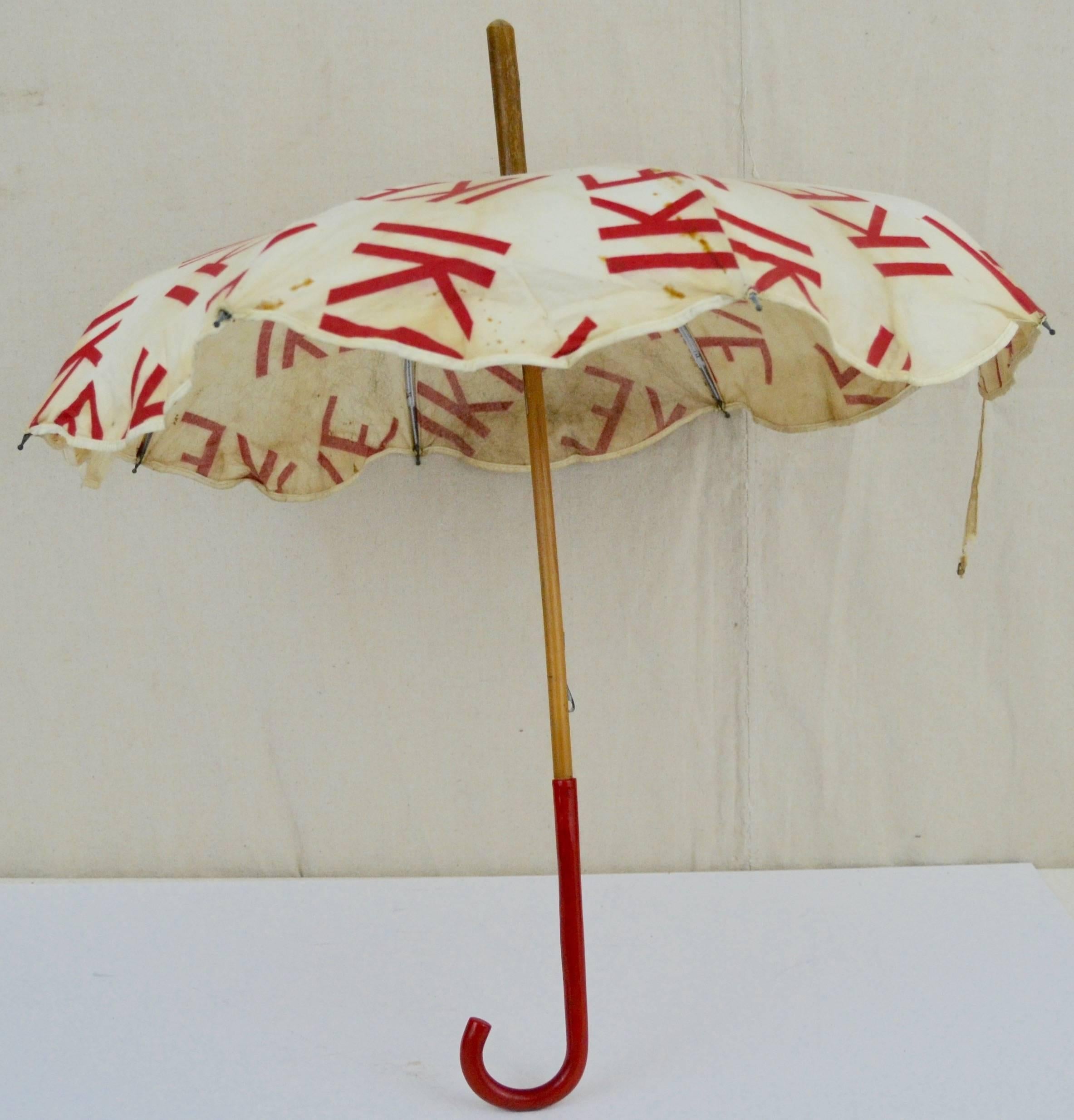 Printed cotton 25.5 in. diameter parasol carried by "Ike Girls" at "Eisenhower Bandwagon" events during the 1956 presidential race. The cloth itself is strong but has foxing and staining and a tear on the strap. It has a red